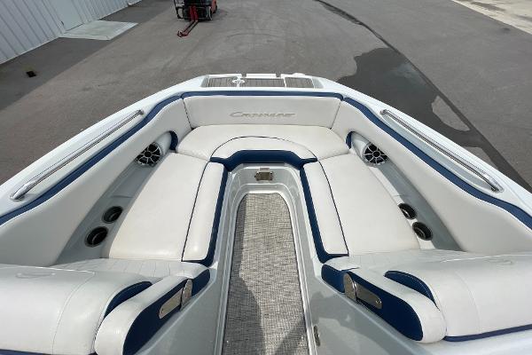 2023 Crownline E235 boat interior with white and blue seating, featuring cup holders and speakers.
