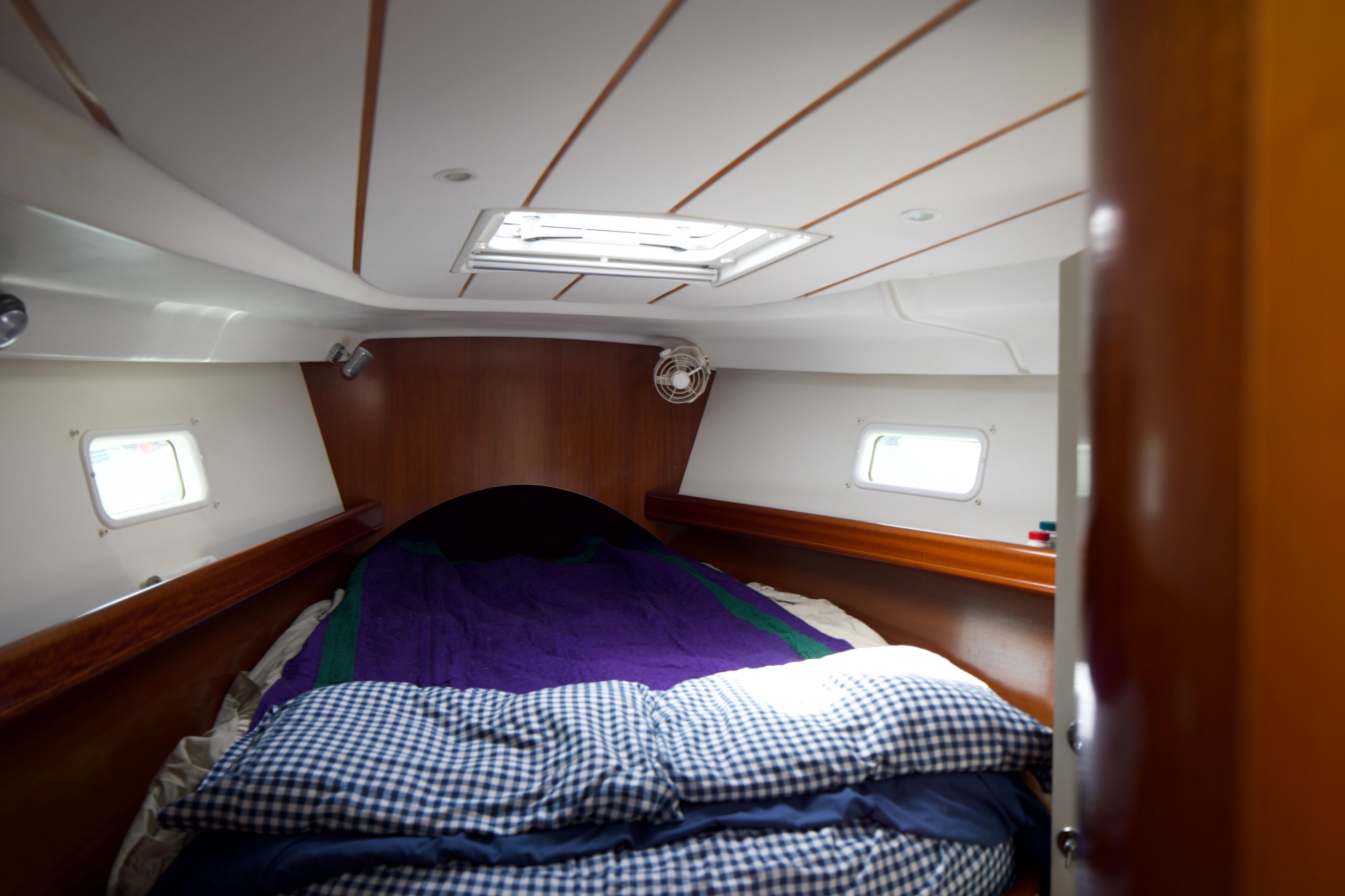 Cozy cabin interior of 2005 Beneteau 423 sailboat with bed and portholes.
