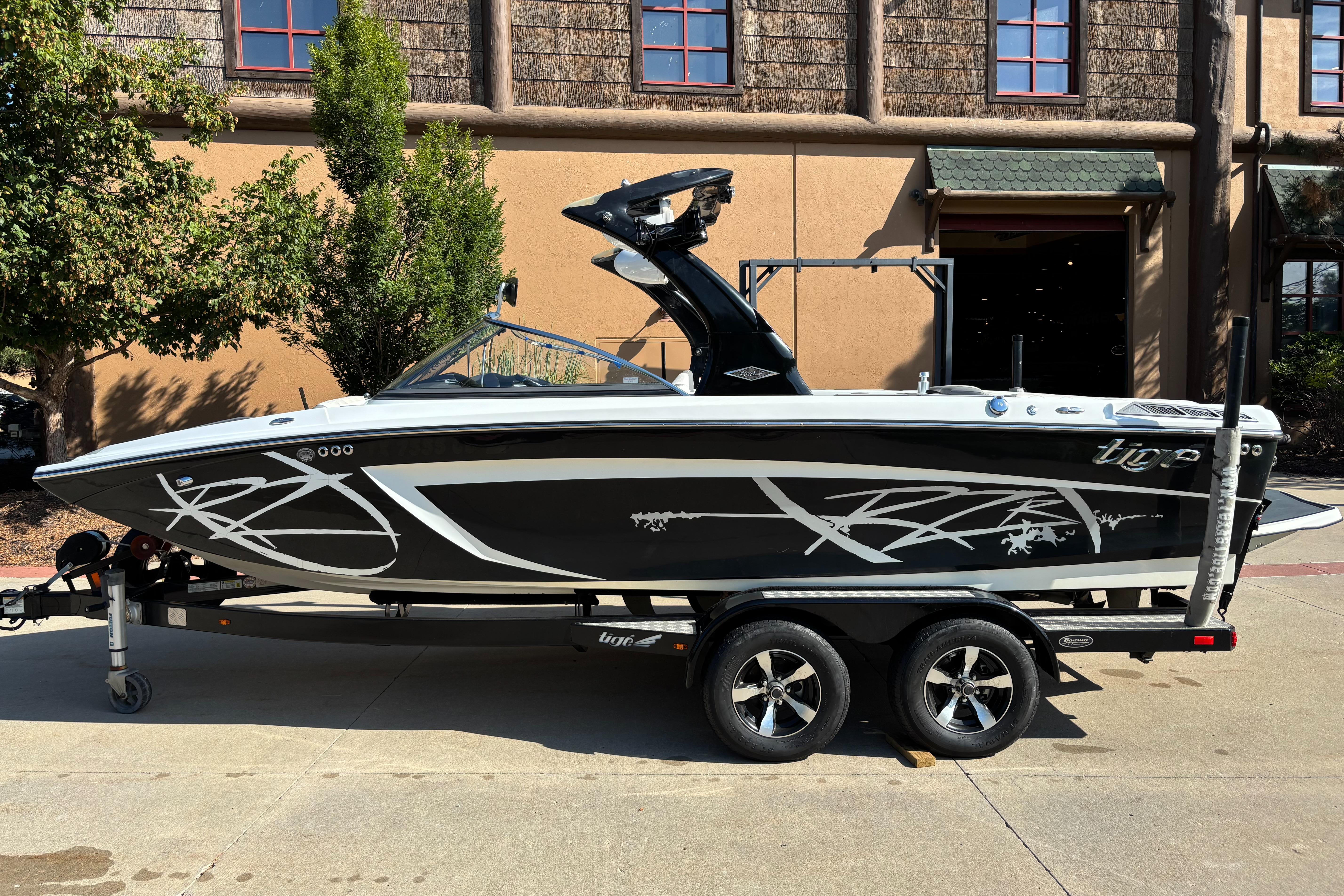 2014 Tigé RZR boat on trailer, black with white graphics, parked outdoors.