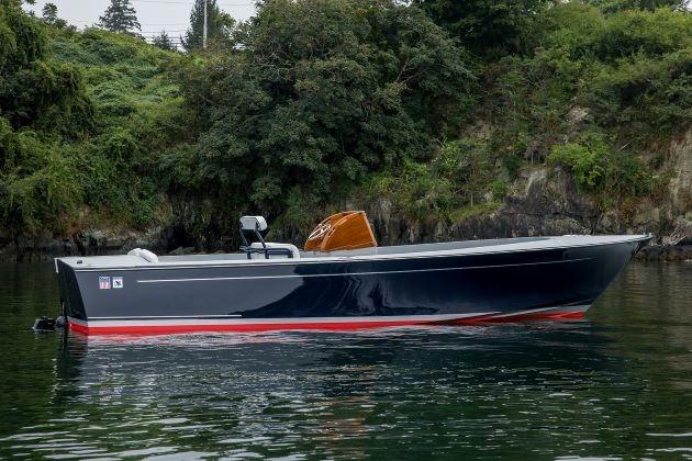 2024 C.W. Hood 26E Electric Runabout on calm water, surrounded by lush greenery.