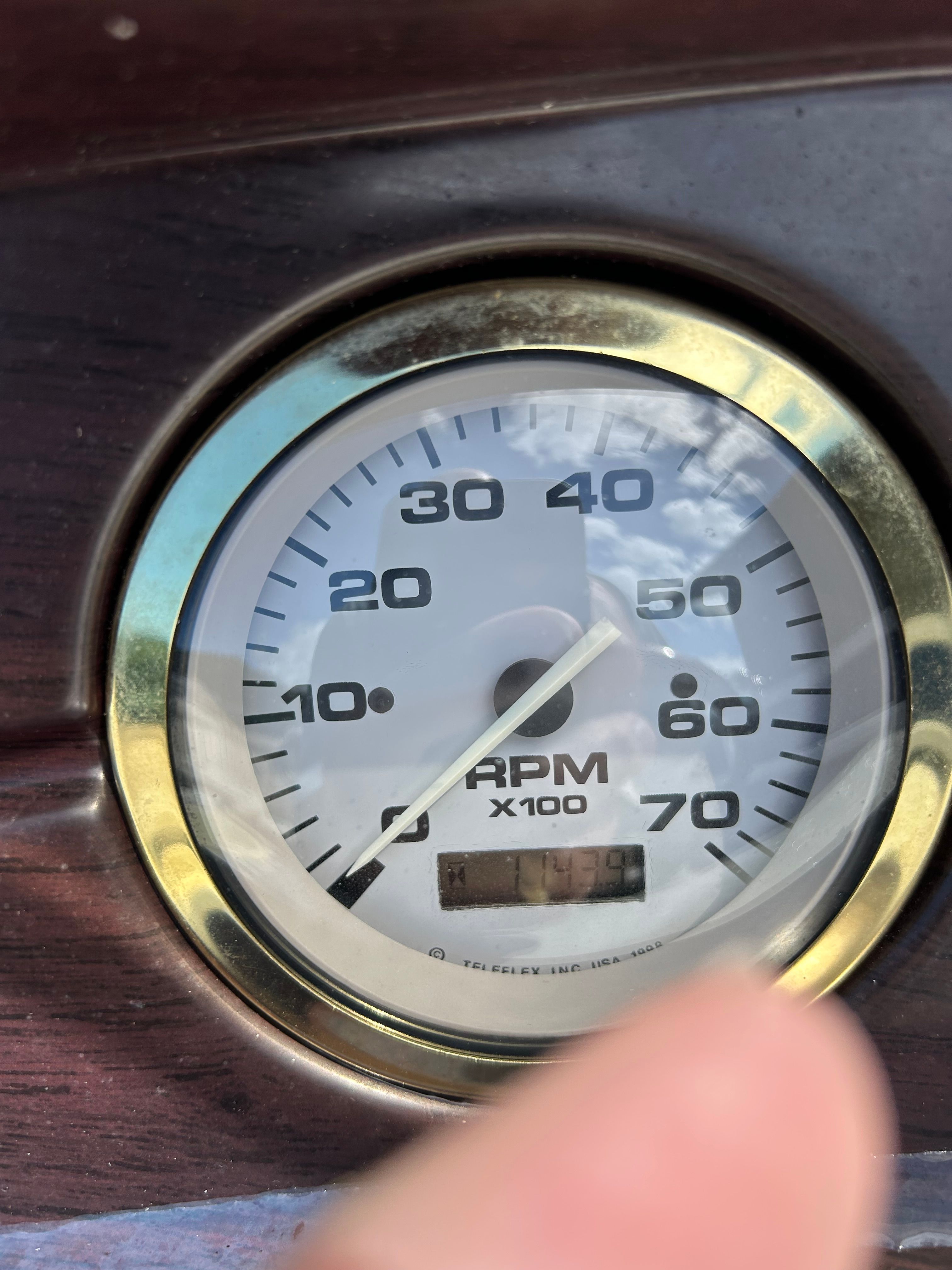 Close-up of a tachometer with a gold rim and wood paneling.