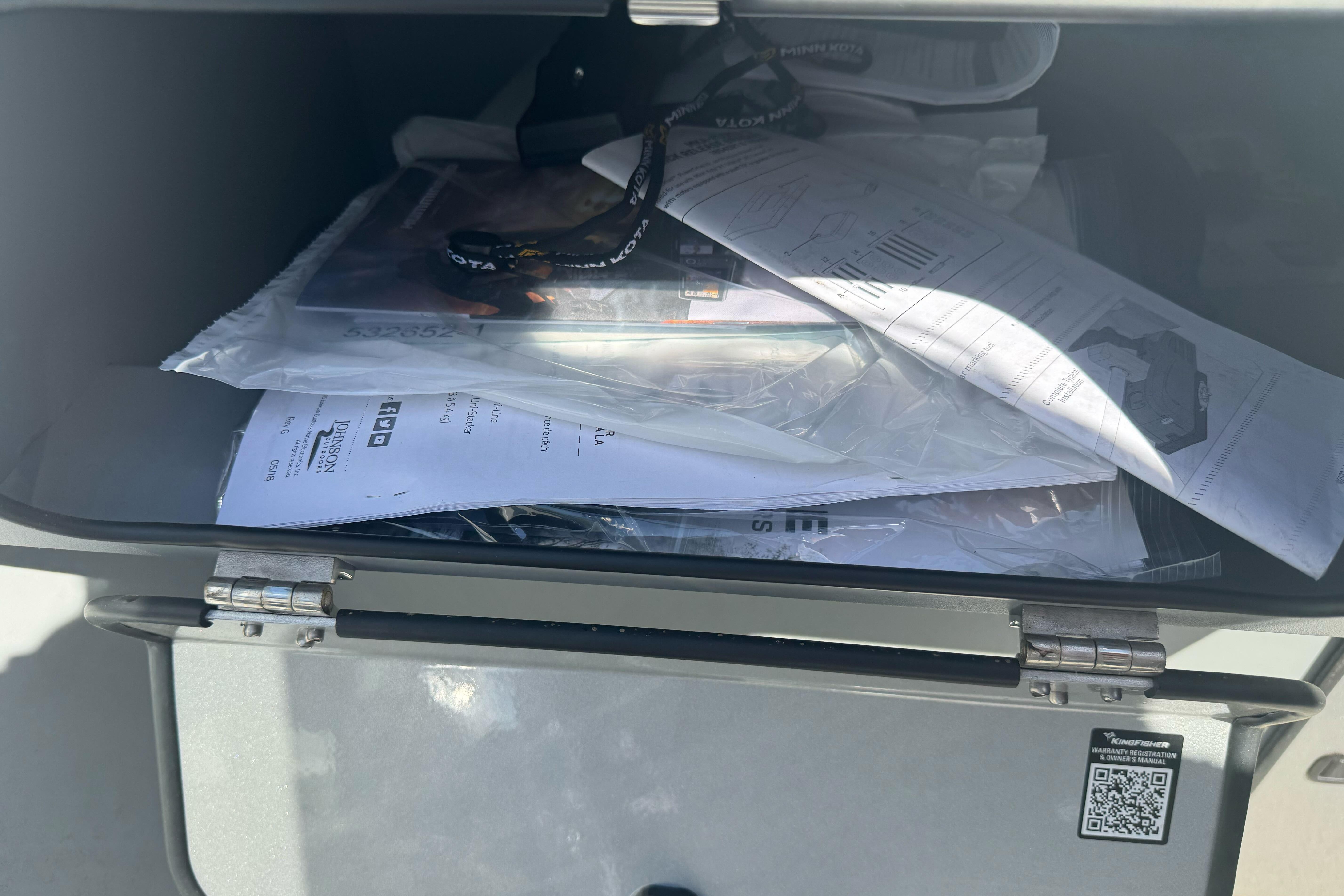 Open storage compartment with documents and lanyard in a 2026 KingFisher 16 Falcon.