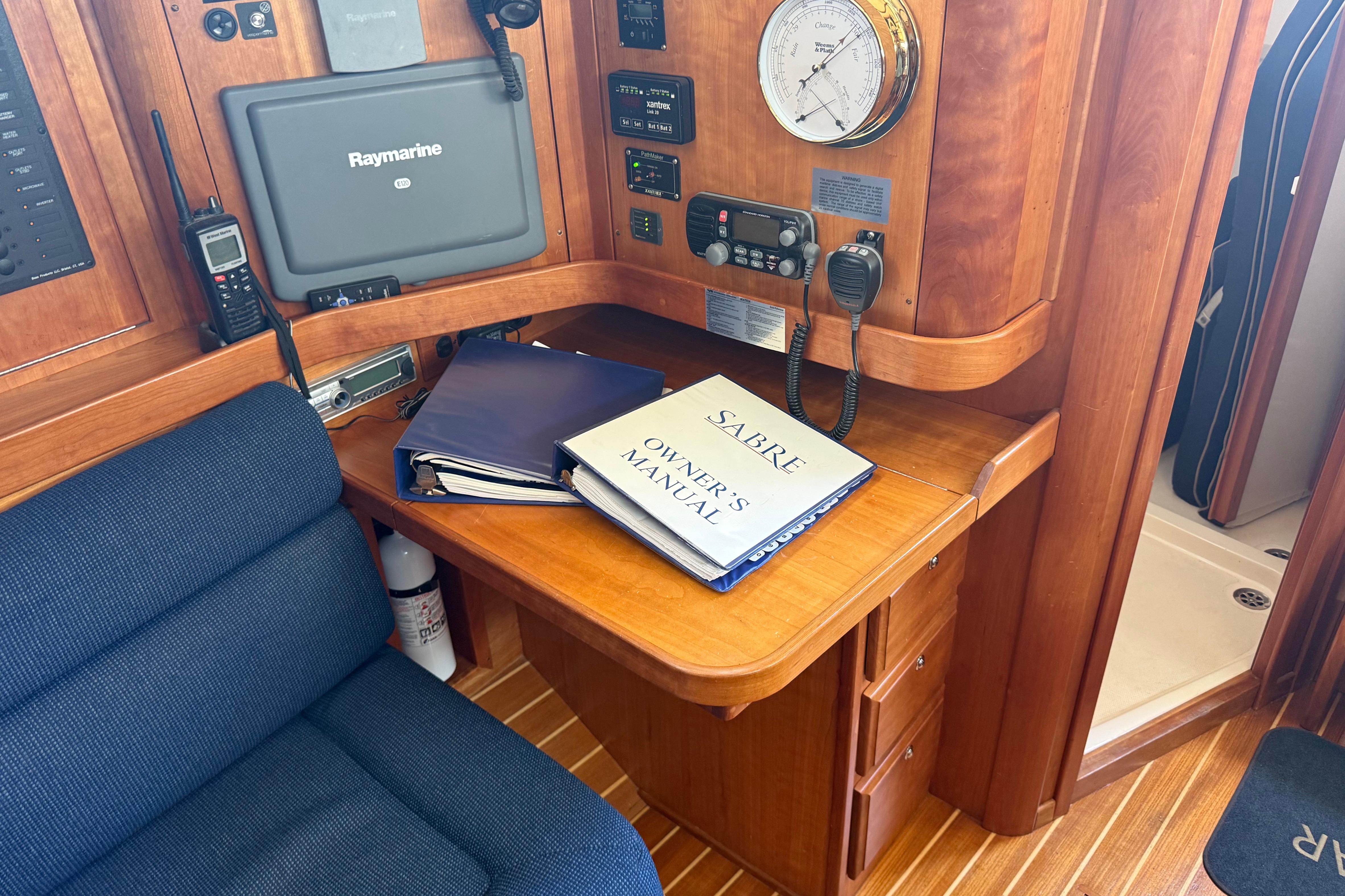 Navigation station with Sabre 386 owner's manual, Raymarine equipment, and communication devices.