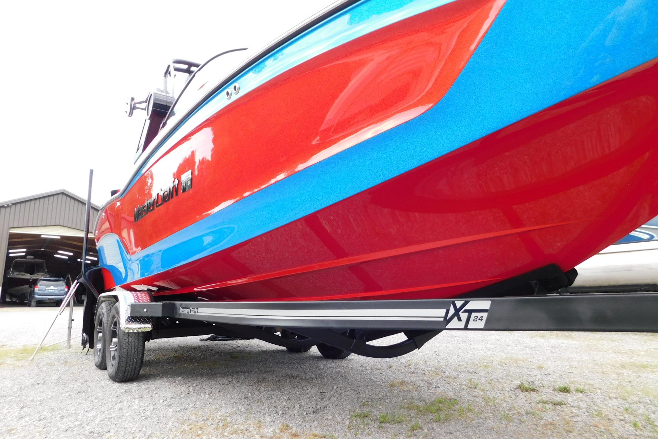 2022 MasterCraft NXT24 boat with vibrant red and blue design on a trailer.