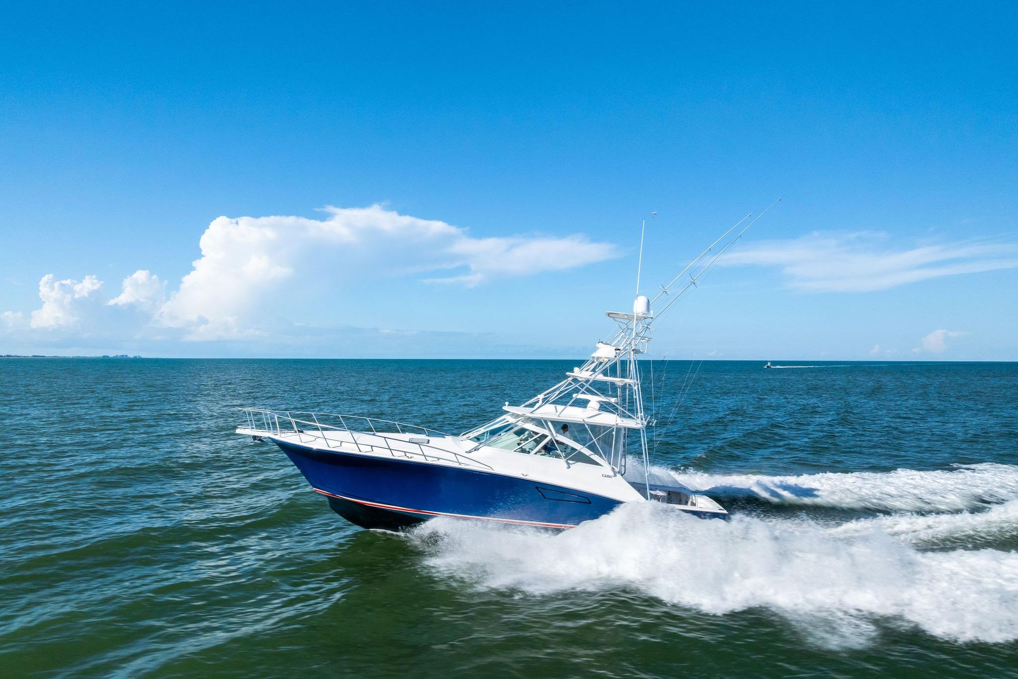 2006 Cabo 45 Express yacht cruising on open sea under clear blue sky.