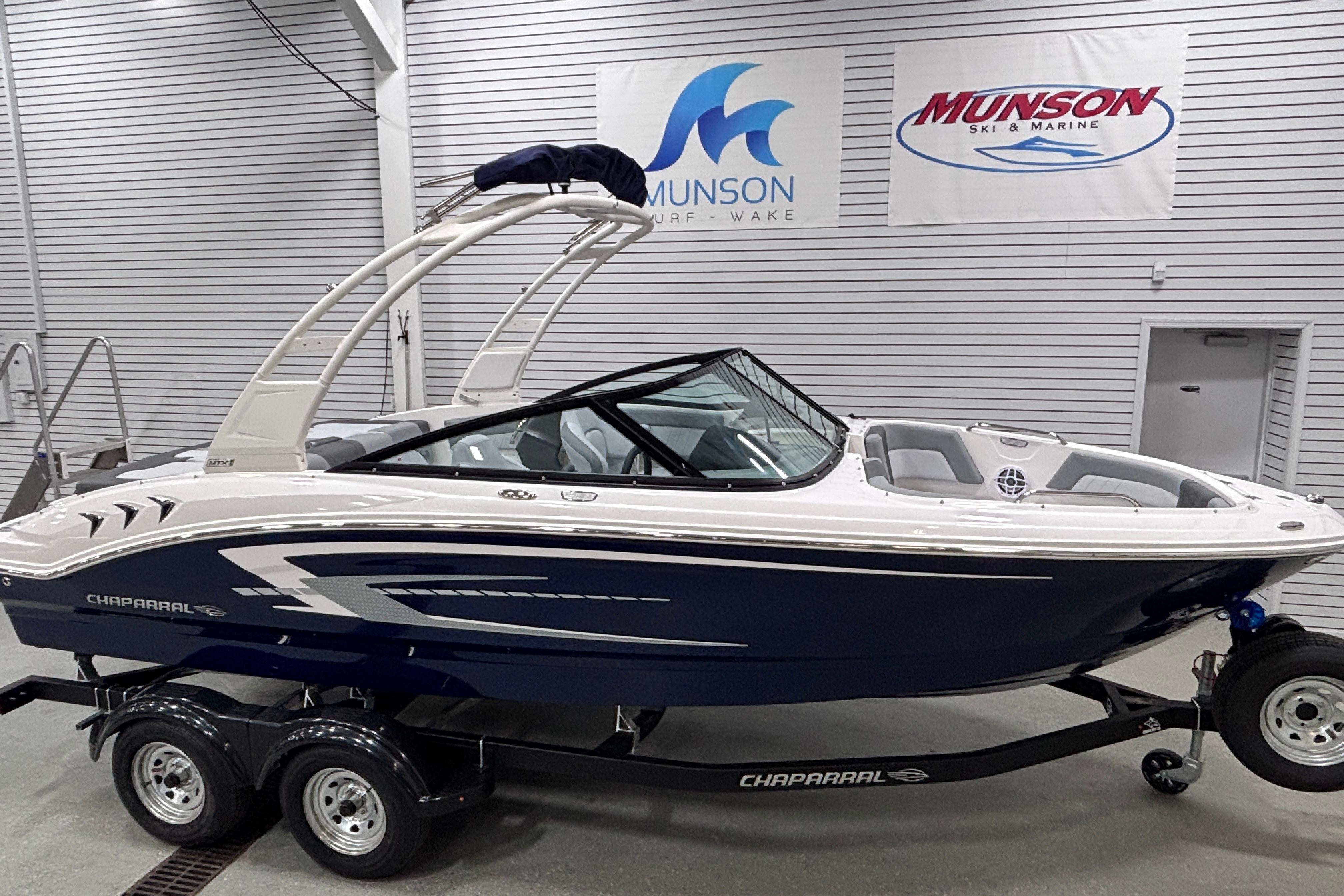 2026 Chaparral 21 SSi boat on trailer in showroom, Munson Ski & Marine banners visible.