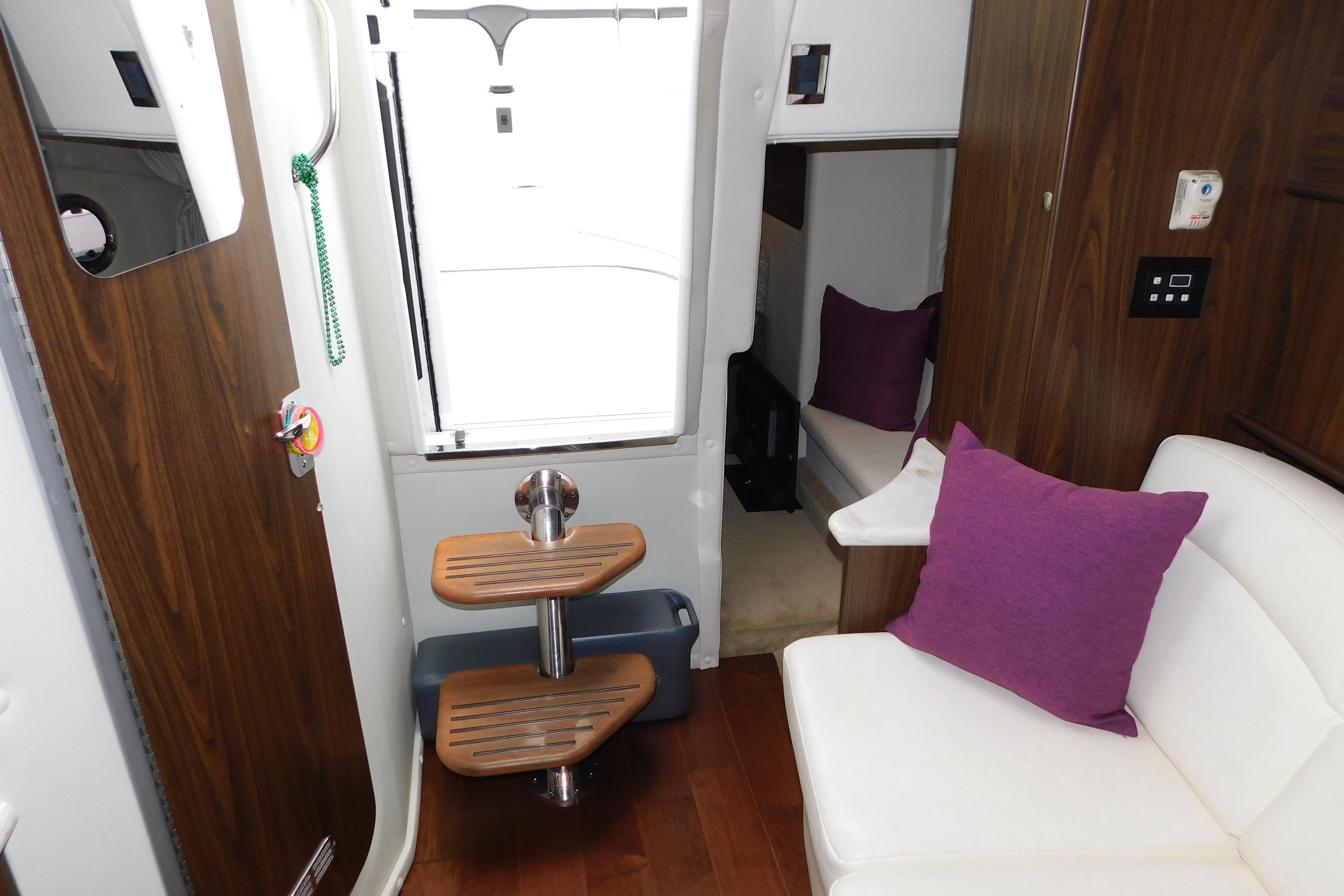 Interior of 2017 Rinker EX 320 boat with wooden steps and purple cushions.