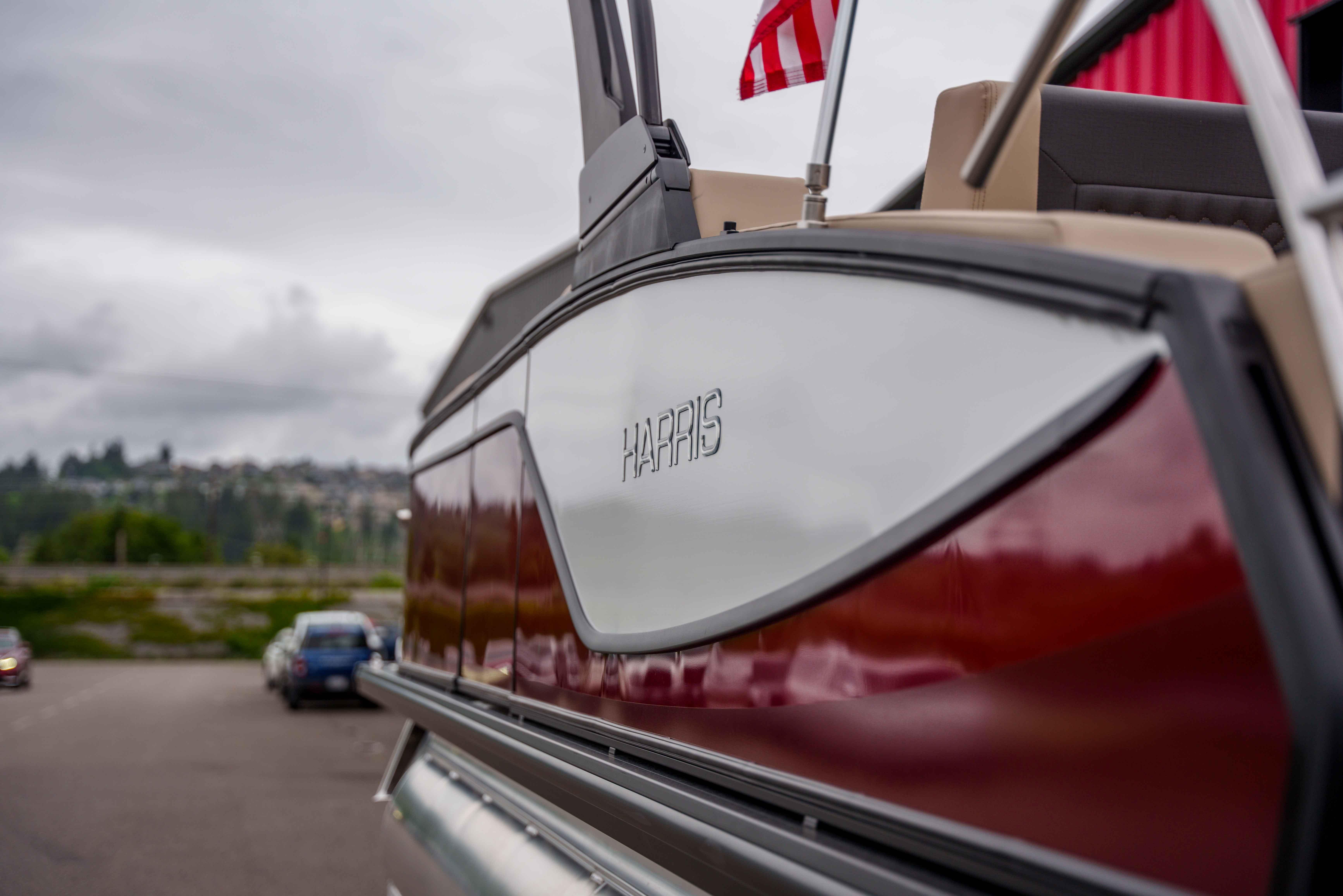 2026 Harris Sunliner 230 pontoon boat with American flag, parked outdoors.