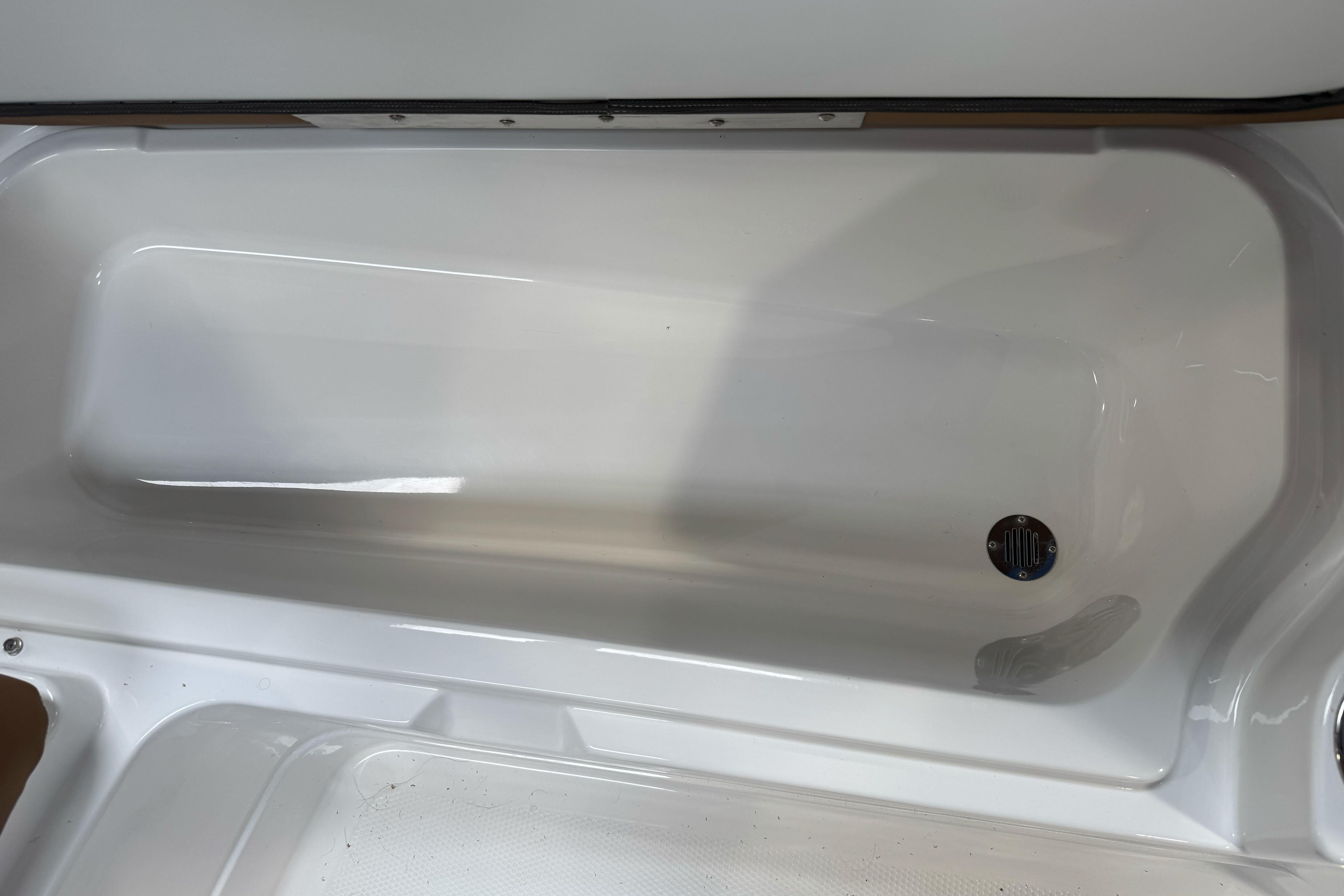 2026 Tahoe 2150 boat storage compartment, white interior, drain plug visible.