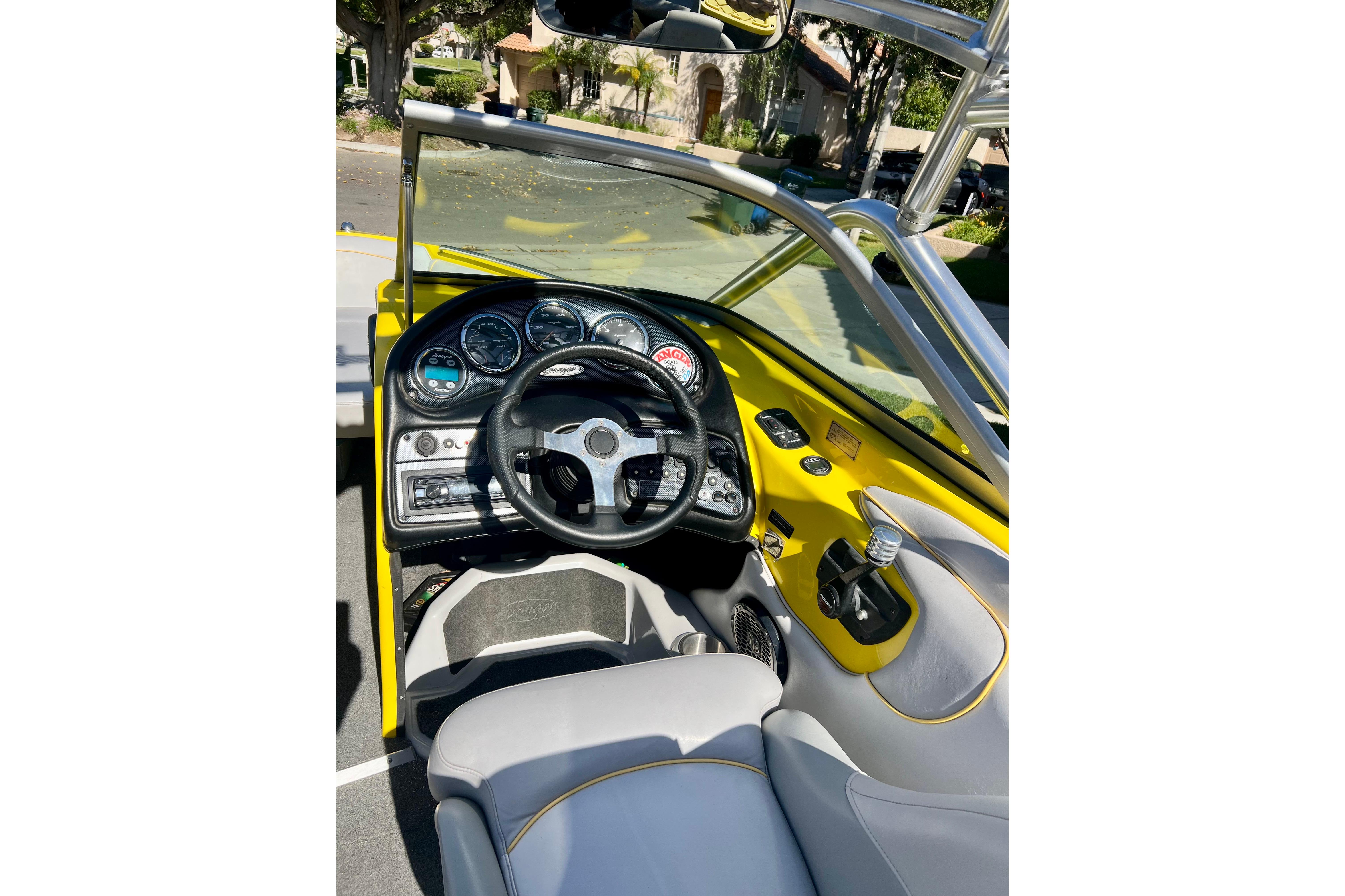 Interior view of a 2006 Sanger V230 boat, featuring a sleek dashboard and steering wheel.
