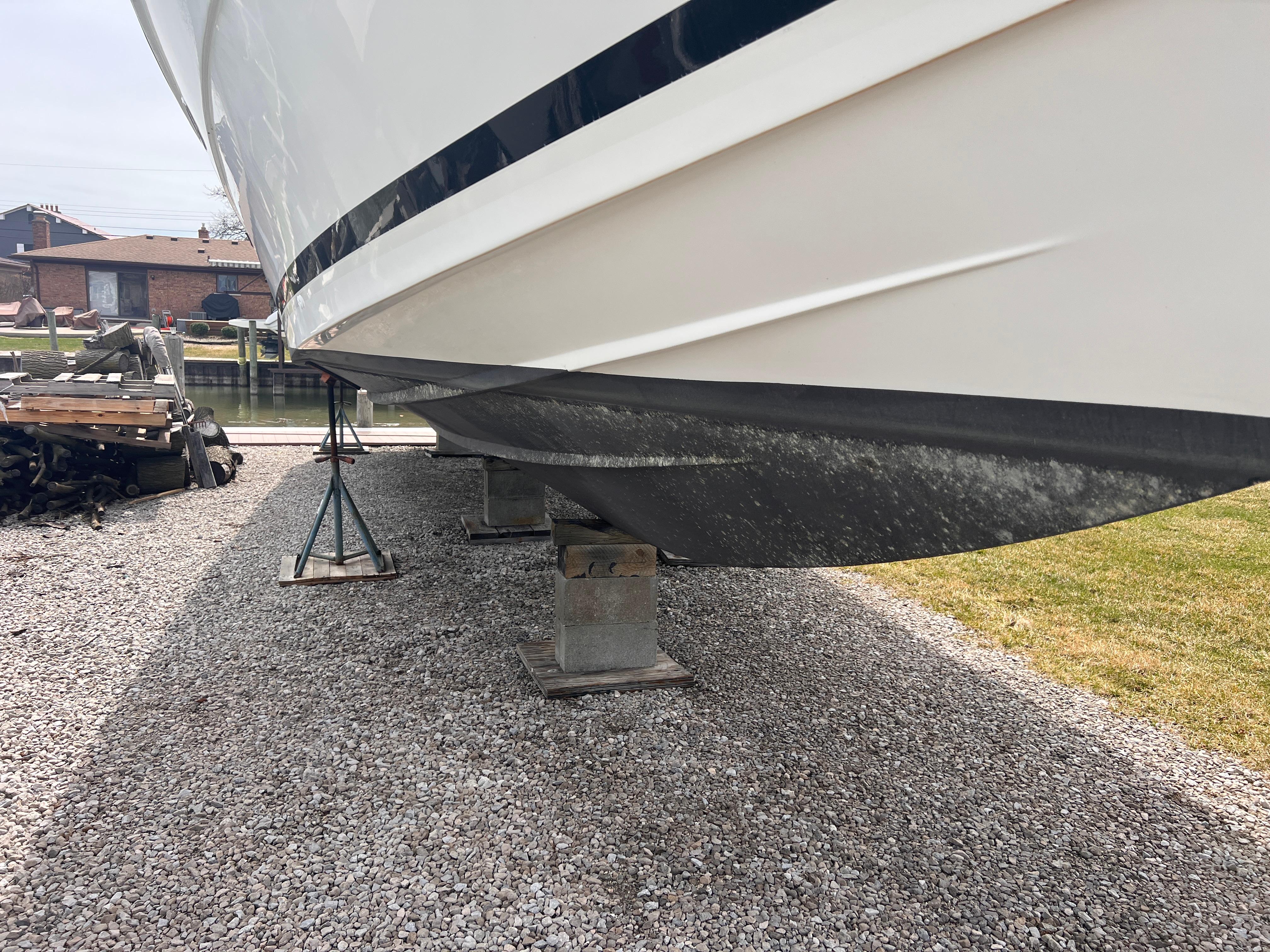 2000 Wellcraft 45 Excalibur boat on stands, side view, gravel ground.