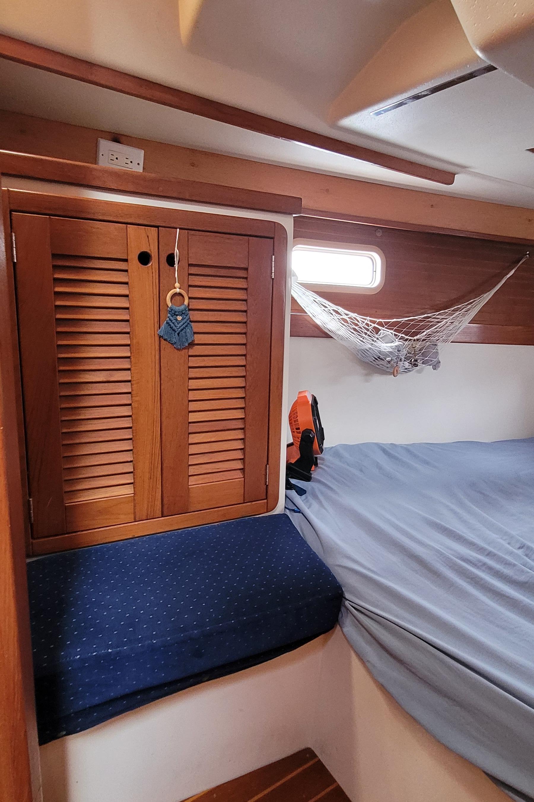 Cozy cabin interior of a 1992 Catalina 42 sailboat with wooden cabinets and a bed.