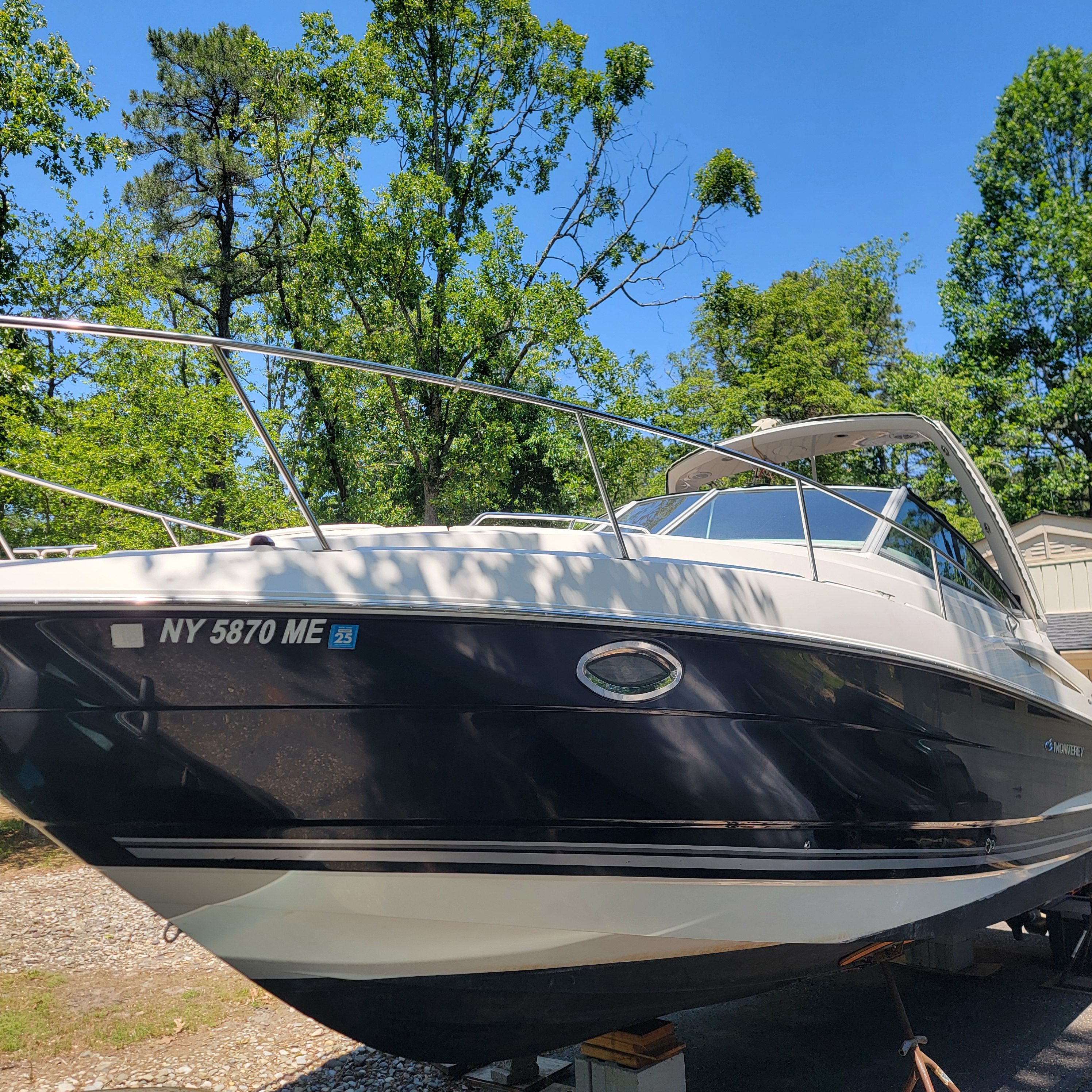 A Monterey 290 Cruiser boat is on a trailer, surrounded by trees.