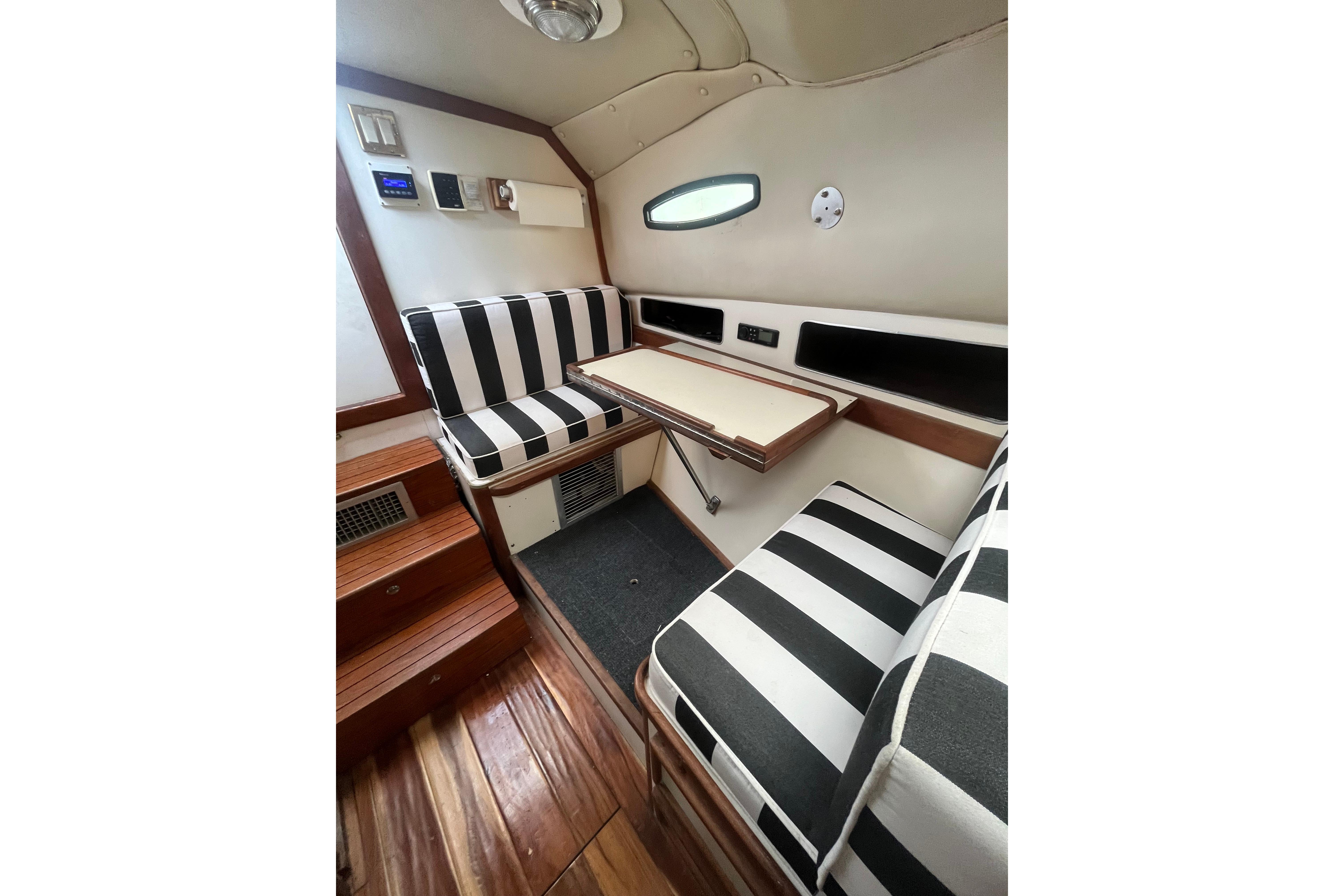 Interior of 1989 Blackfin 31 Combi boat with striped seating and wooden flooring.