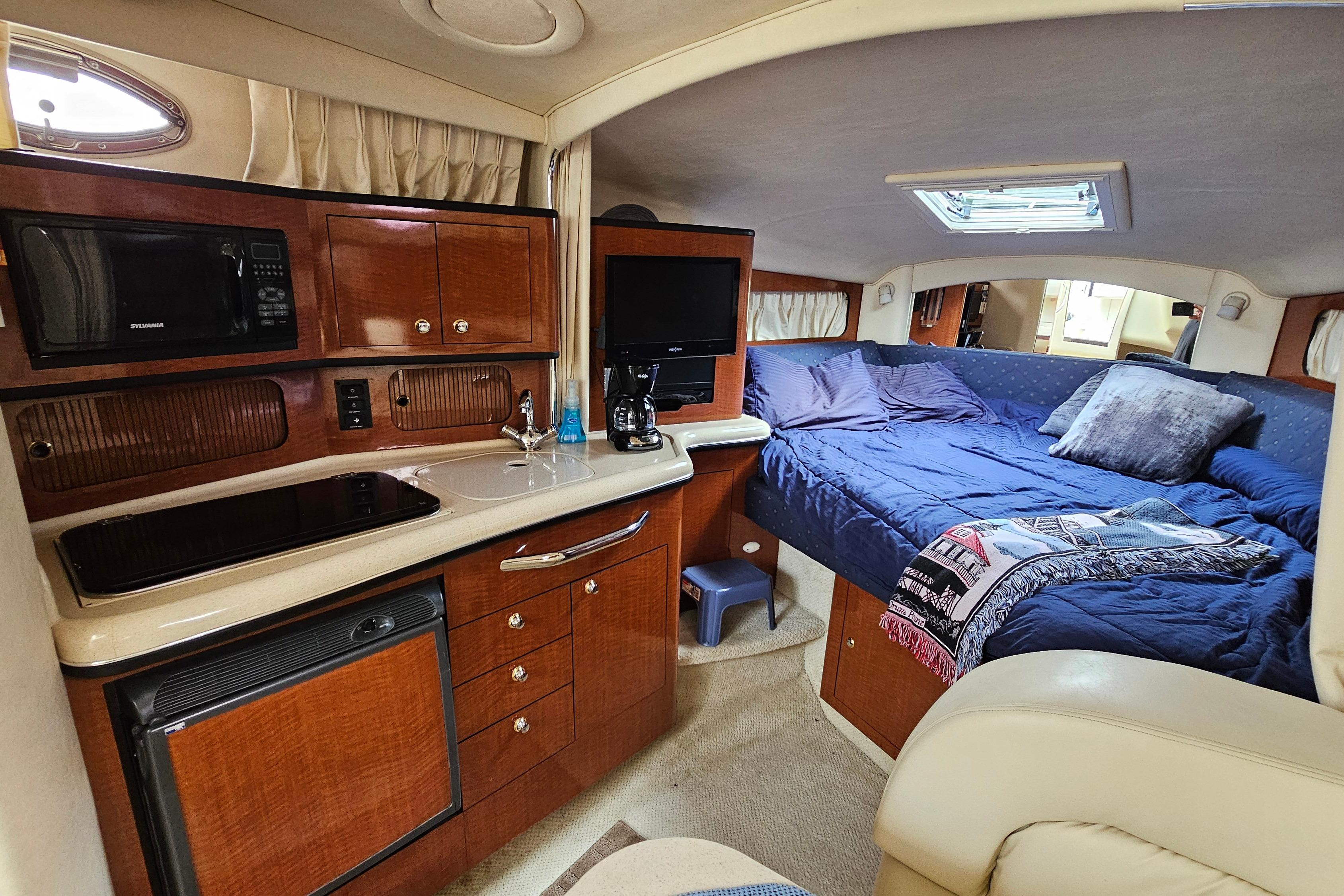 Interior of 2003 Sea Ray 300 Sundancer with kitchenette and cozy sleeping area.