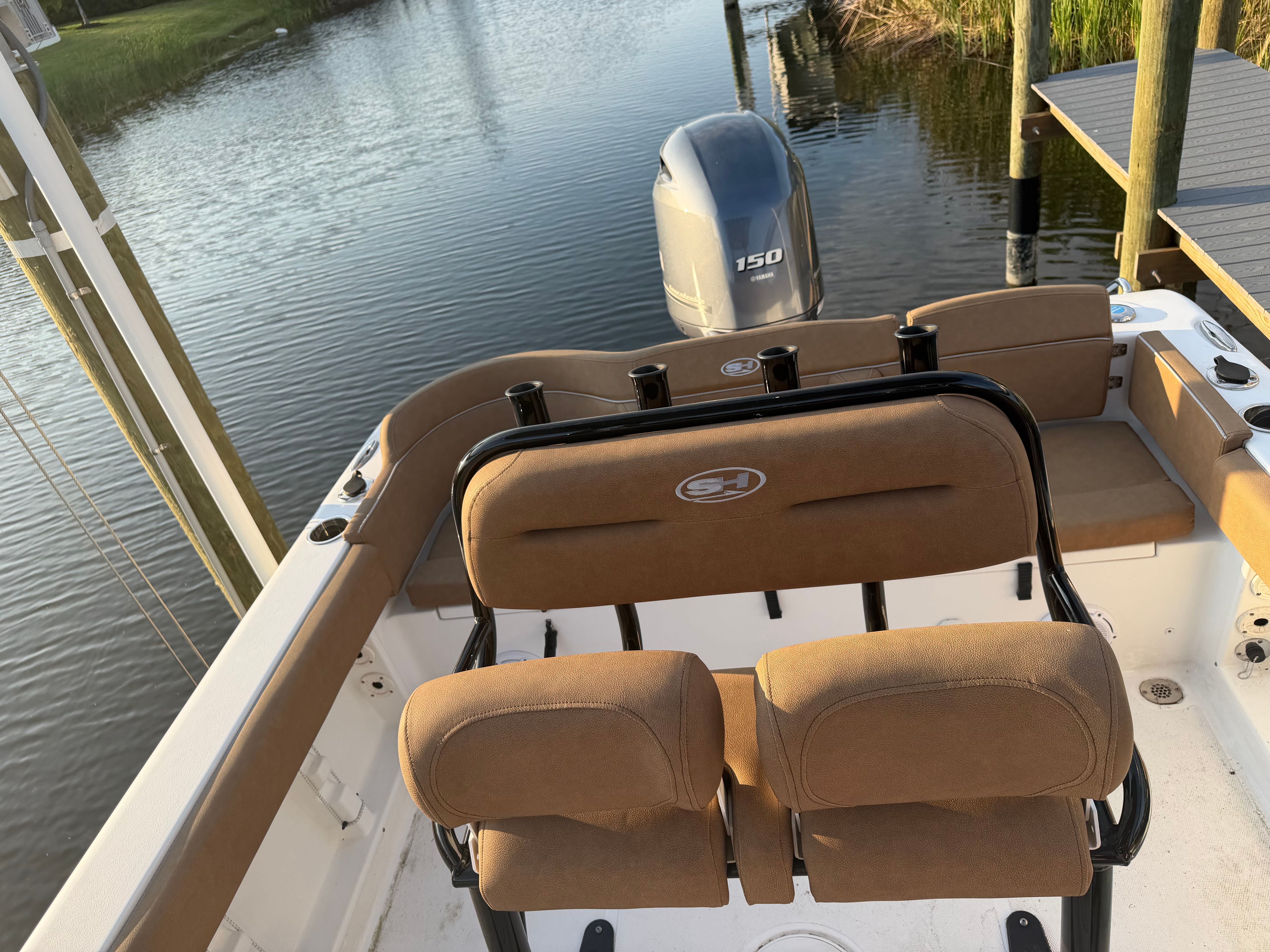 The image shows the cockpit of a 2024 Sea Hunt Ultra 219 boat. It is docked by the water.