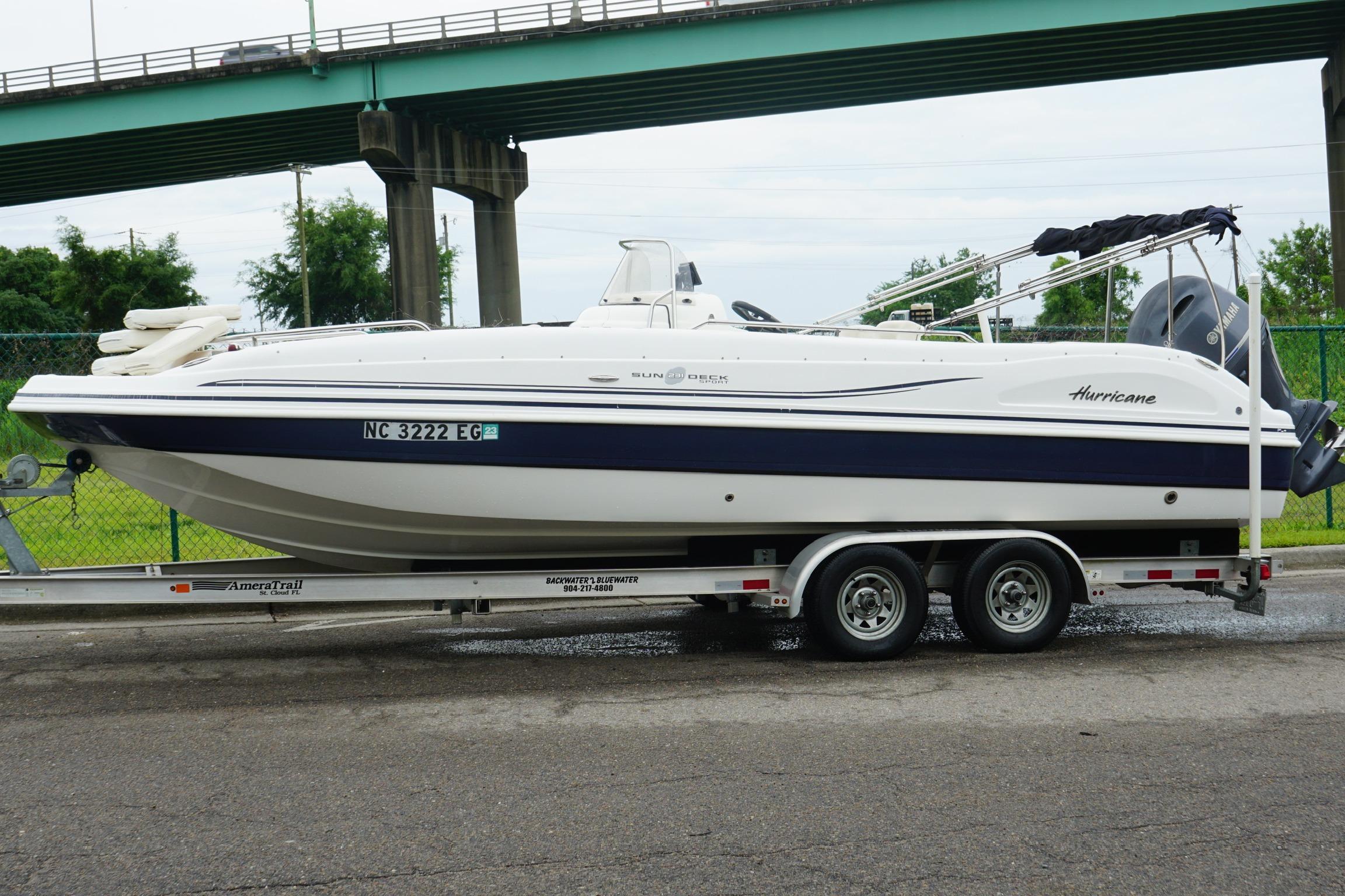 2015 Hurricane SunDeck Sport 231 OB boat on trailer under bridge.
