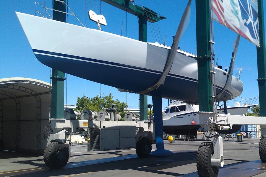 1980 Santa Cruz SC 50 sailboat being lifted at a marina under clear blue skies.