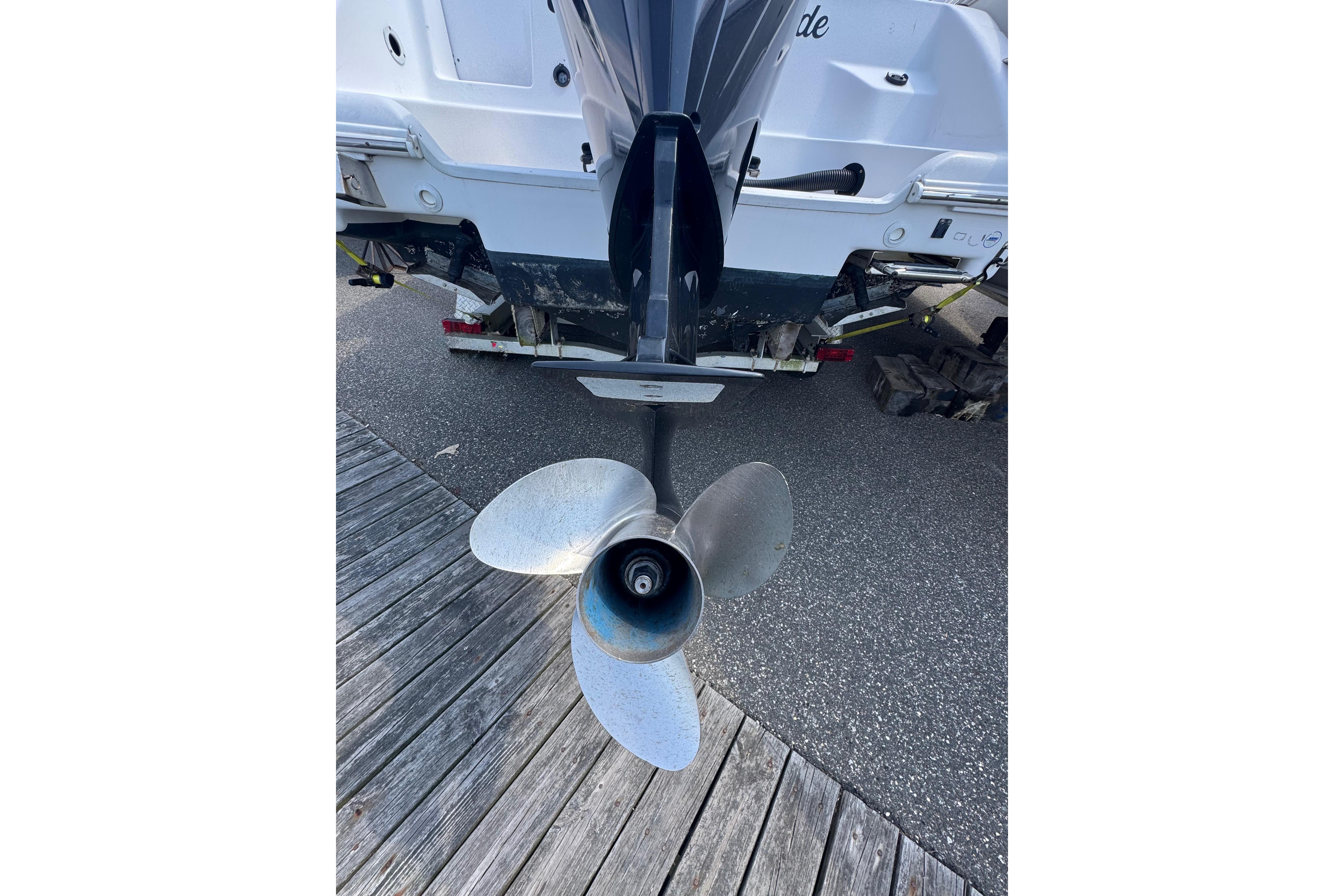 Propeller of a 2002 Pro-Line 23 Sport boat on a wooden dock.