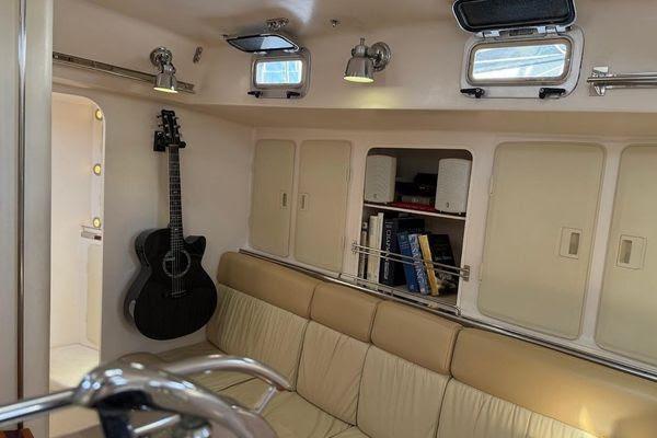 Interior of 2011 Reliance 44 yacht with beige seating, guitar, and bookshelf.