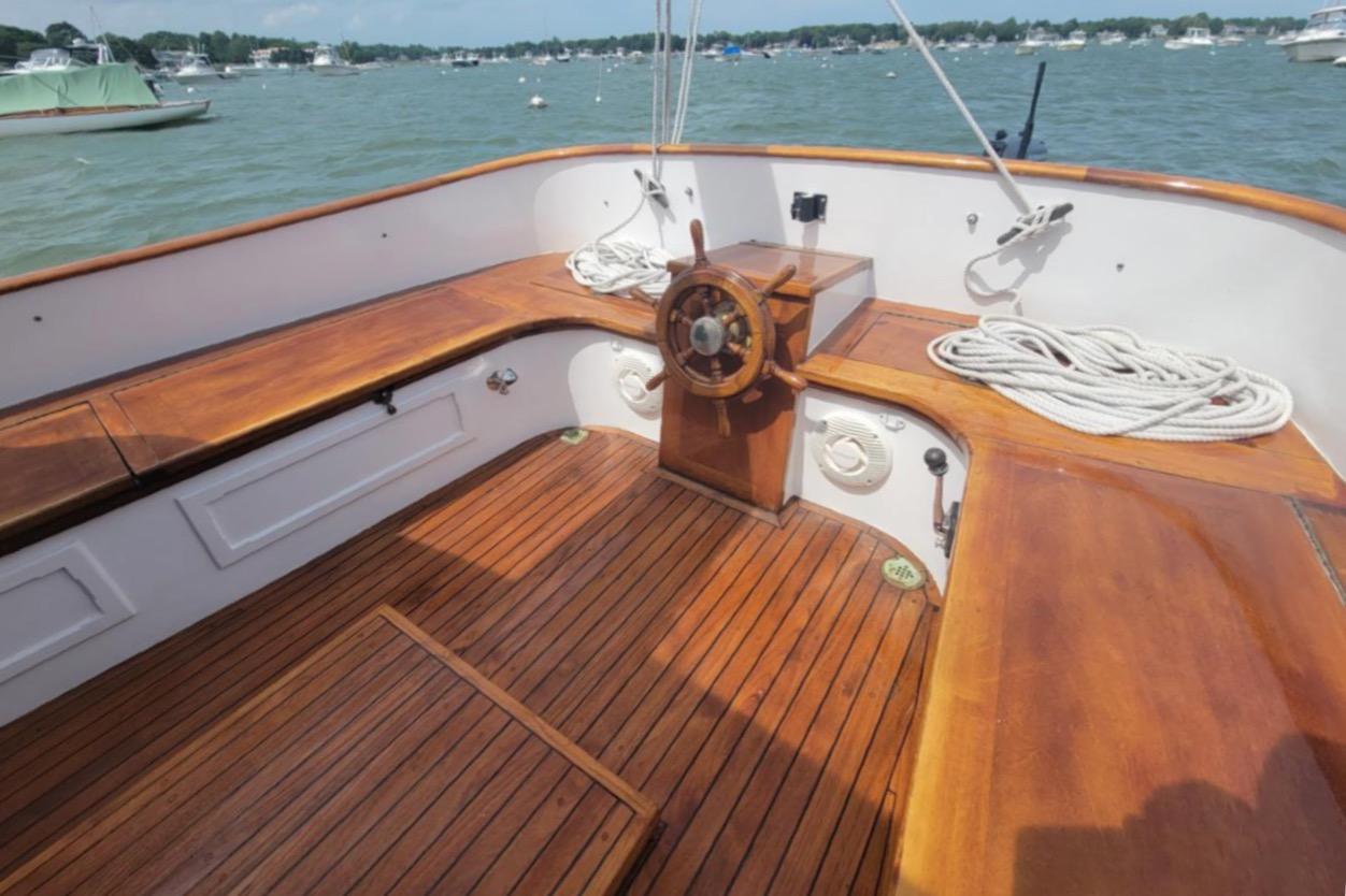 1978 Cape Cod Catboat Ted Brewer with wooden deck and helm, docked on a sunny day.