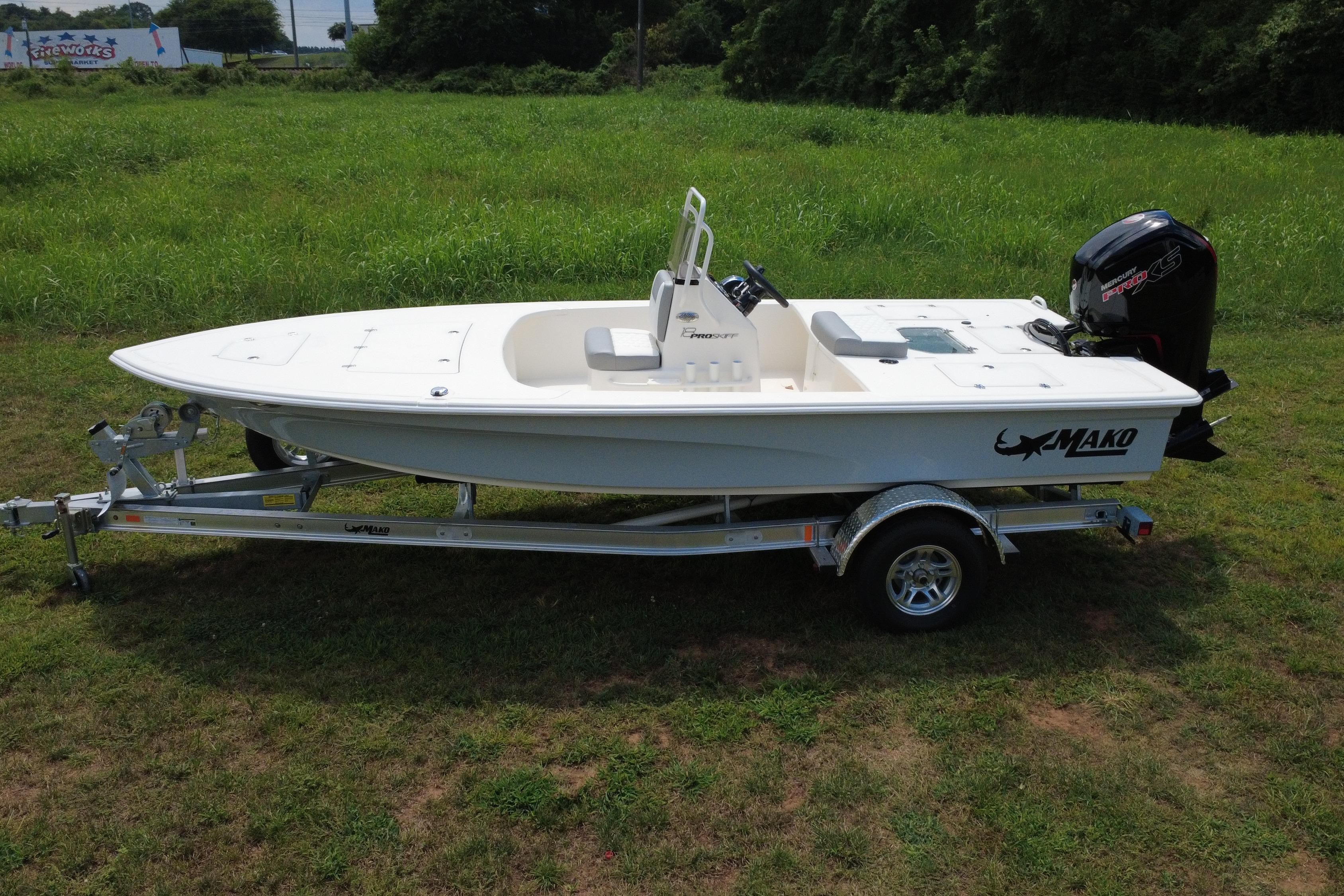 2026 Mako 18 Pro Skiff boat on trailer, parked on grassy field.