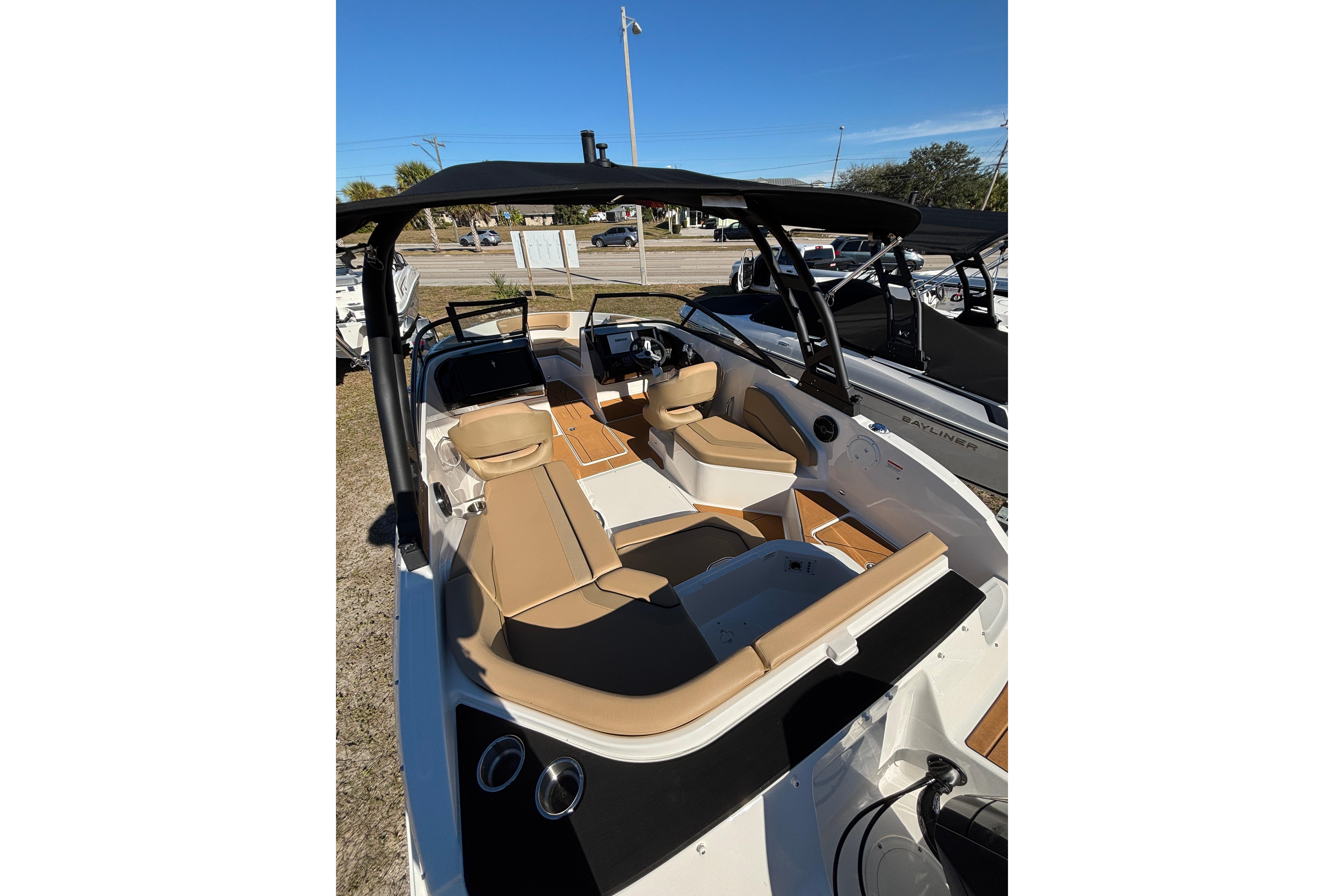 2025 Bayliner V20 boat with tan seating and black canopy, parked outdoors.