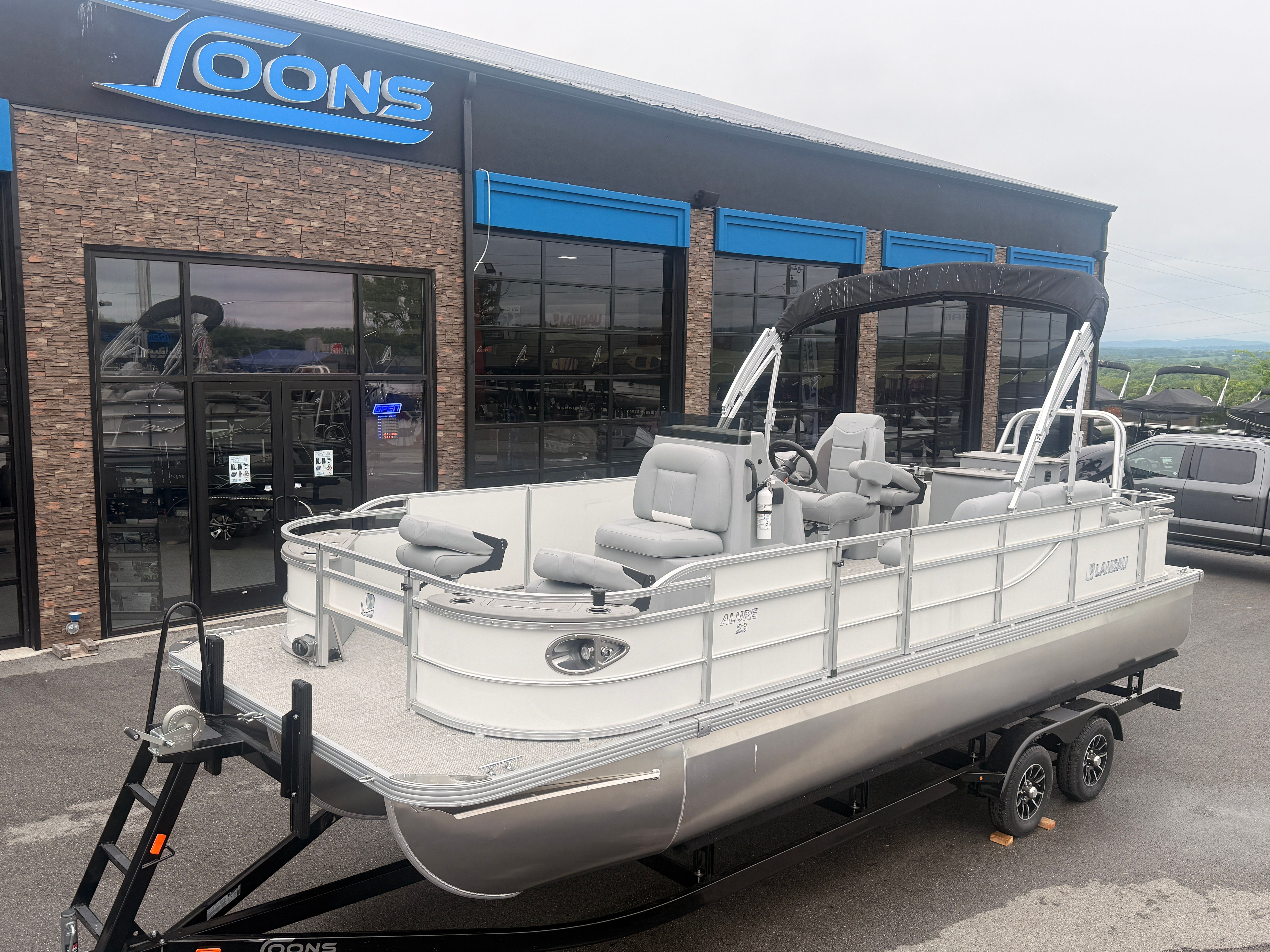 2026 Landau Alure 23CC Fish pontoon boat outside a store.