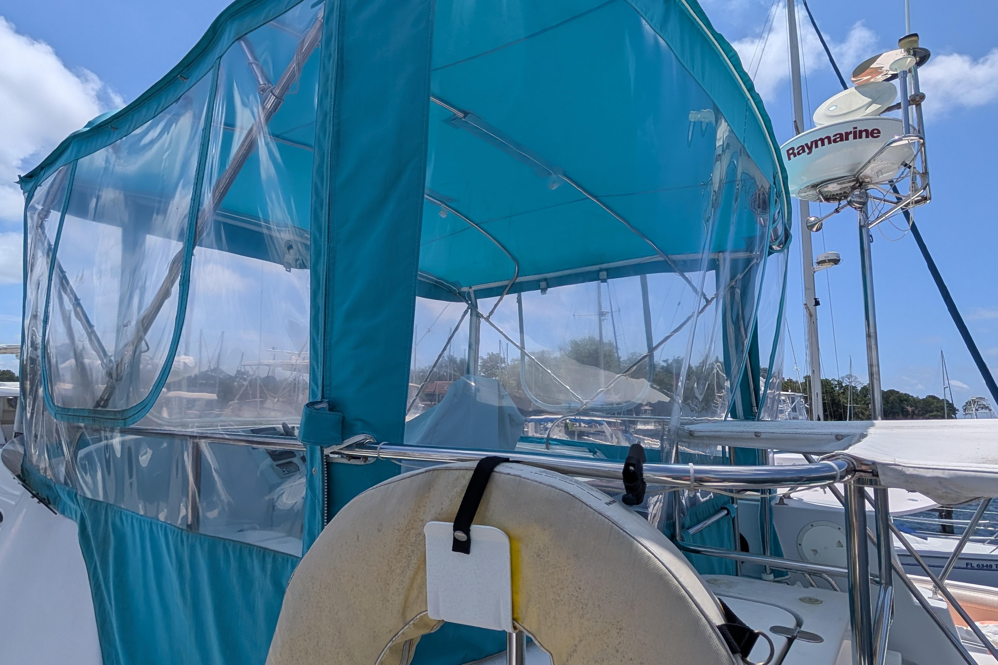2004 PDQ 34 Powercat with blue canopy and Raymarine equipment in marina.