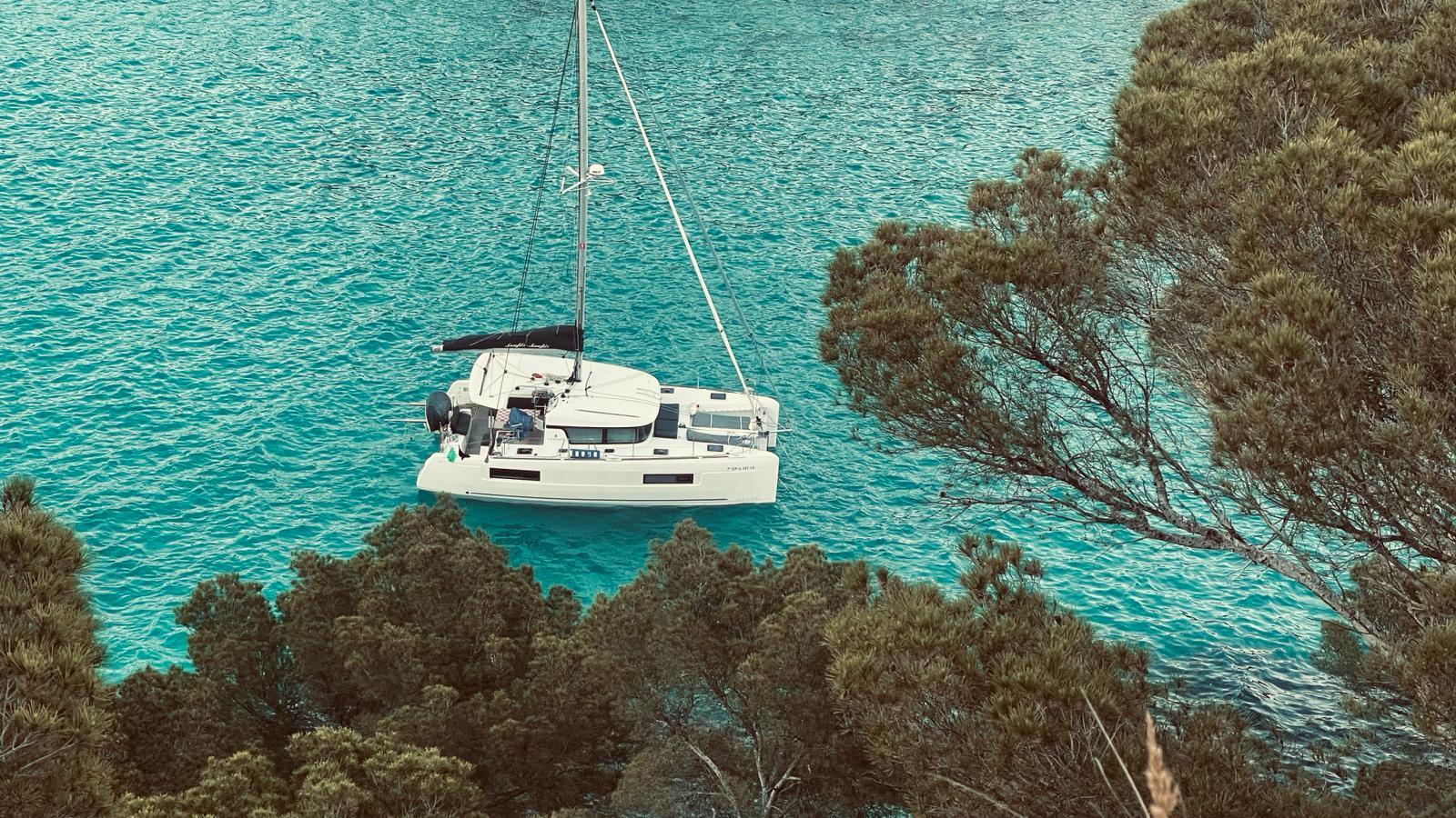 2019 Lagoon 40 catamaran anchored in turquoise waters, surrounded by lush greenery.
