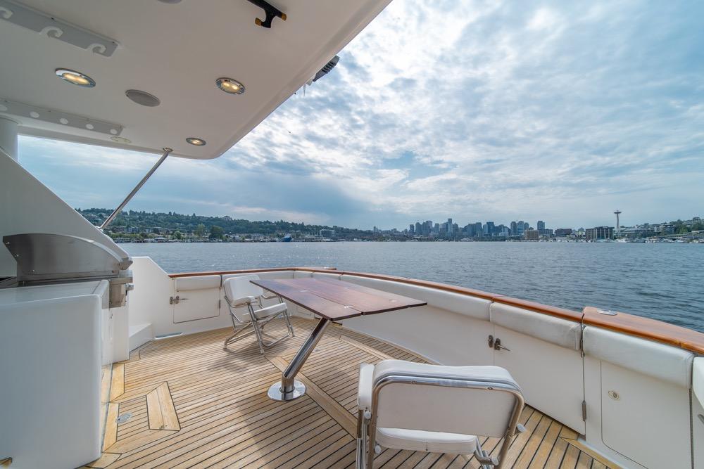 2005 Ocean Alexander 64 Motoryacht deck with city skyline view, featuring seating and table.