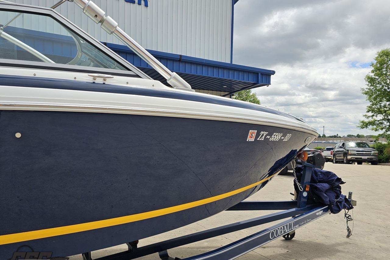 2010 Cobalt 232 WSS boat on trailer, parked outdoors near a building.