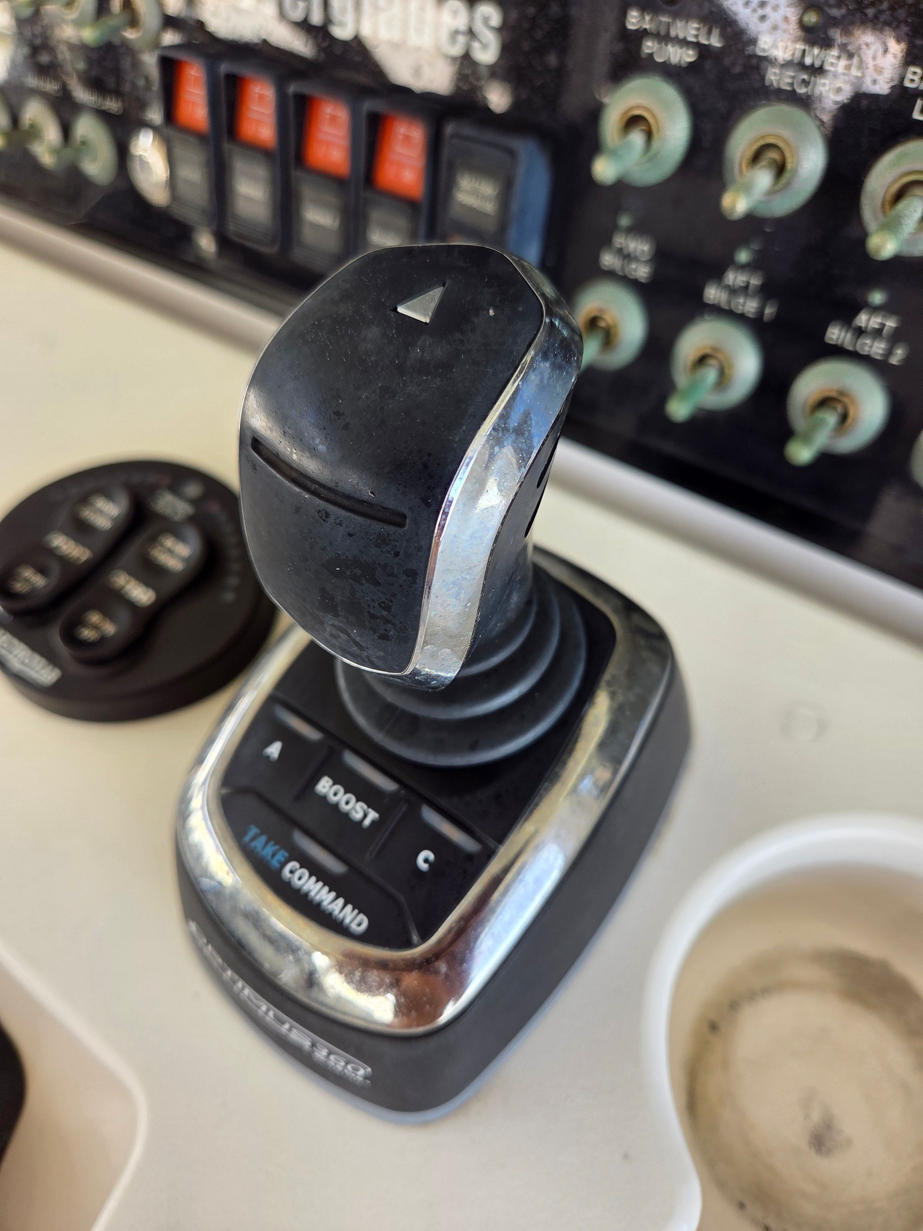 Close-up of a control lever on a boat, surrounded by switches and buttons.