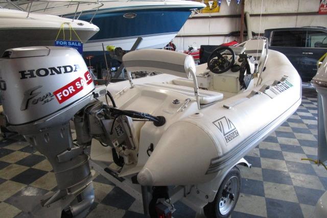 2000 Zodiac Yachtline 340DL inflatable boat with Honda outboard motor, displayed for sale indoors.