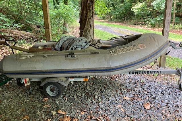 Inflatable boat on trailer, surrounded by trees, associated with 2000 Mainship 430 Trawler.
