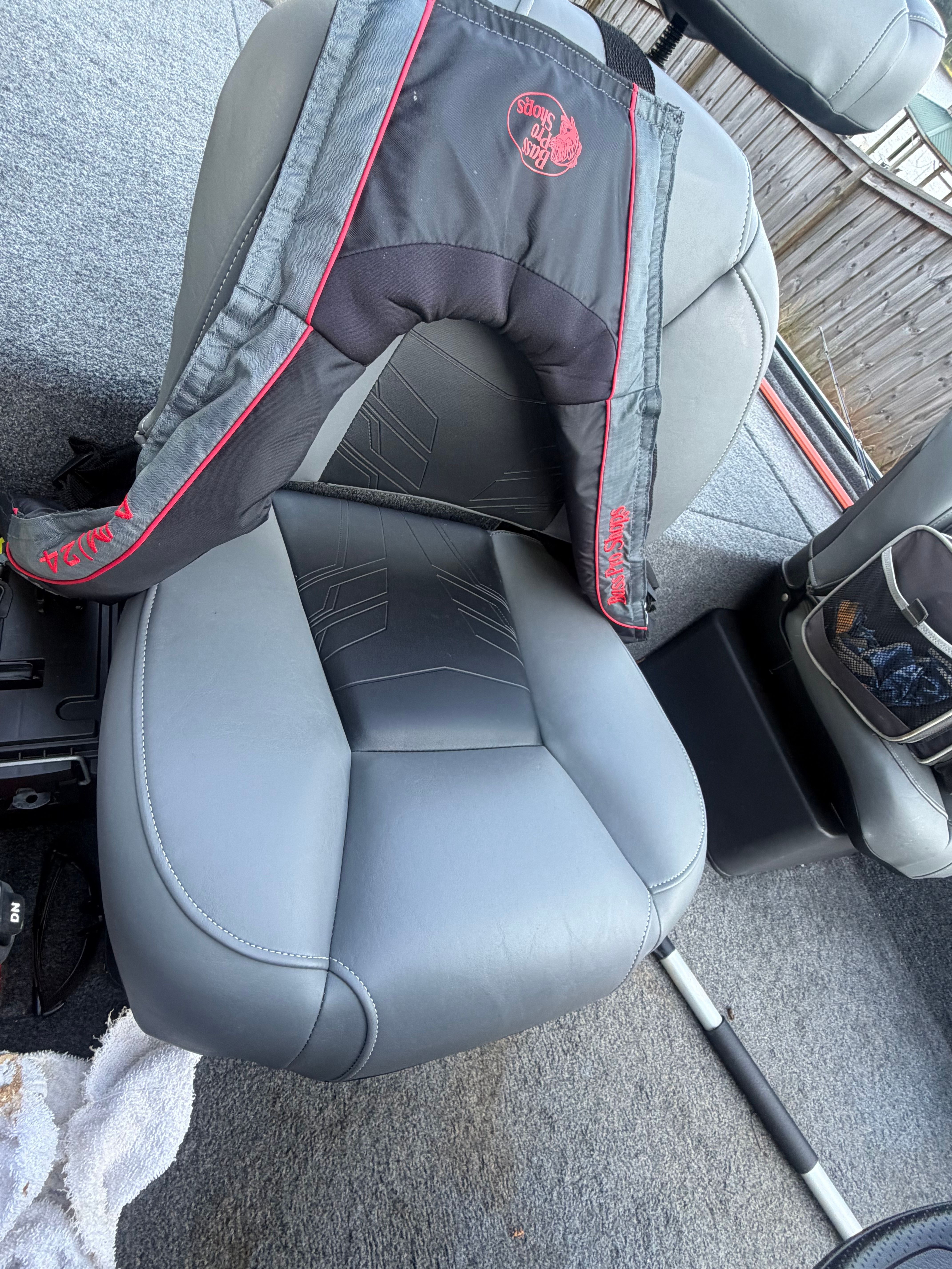A gray boat seat with a life jacket on it, surrounded by gray carpeting.