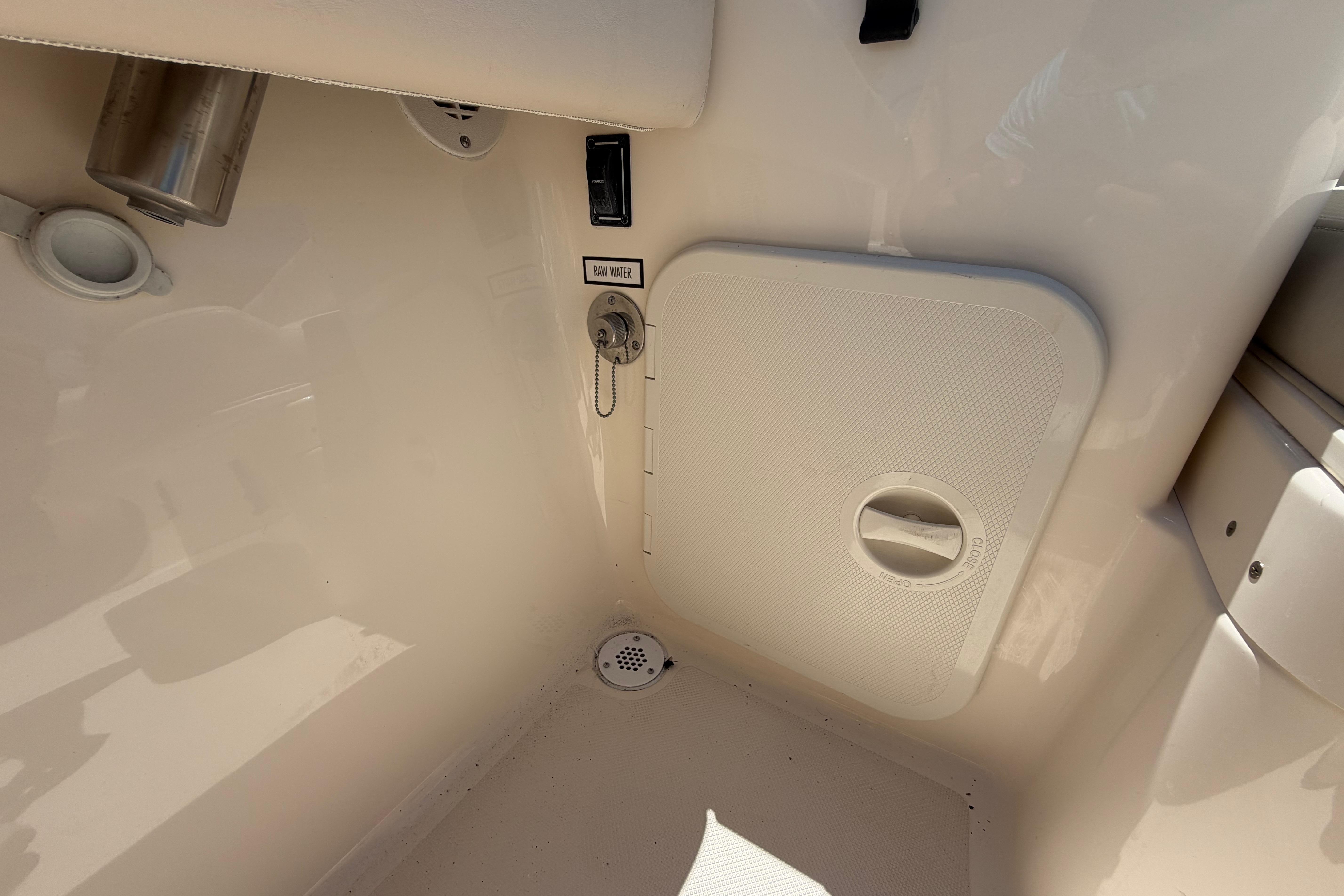 Interior view of a 2010 Pursuit OS 255 Offshore boat, featuring a raw water access panel.