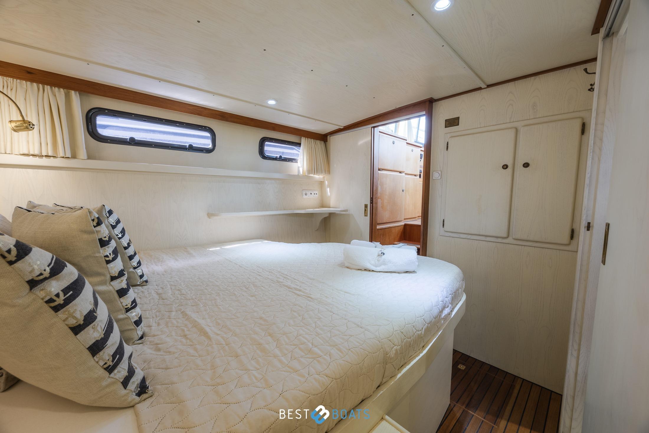 Cozy cabin interior of 1992 Linssen 37 SE yacht with bed and portholes.