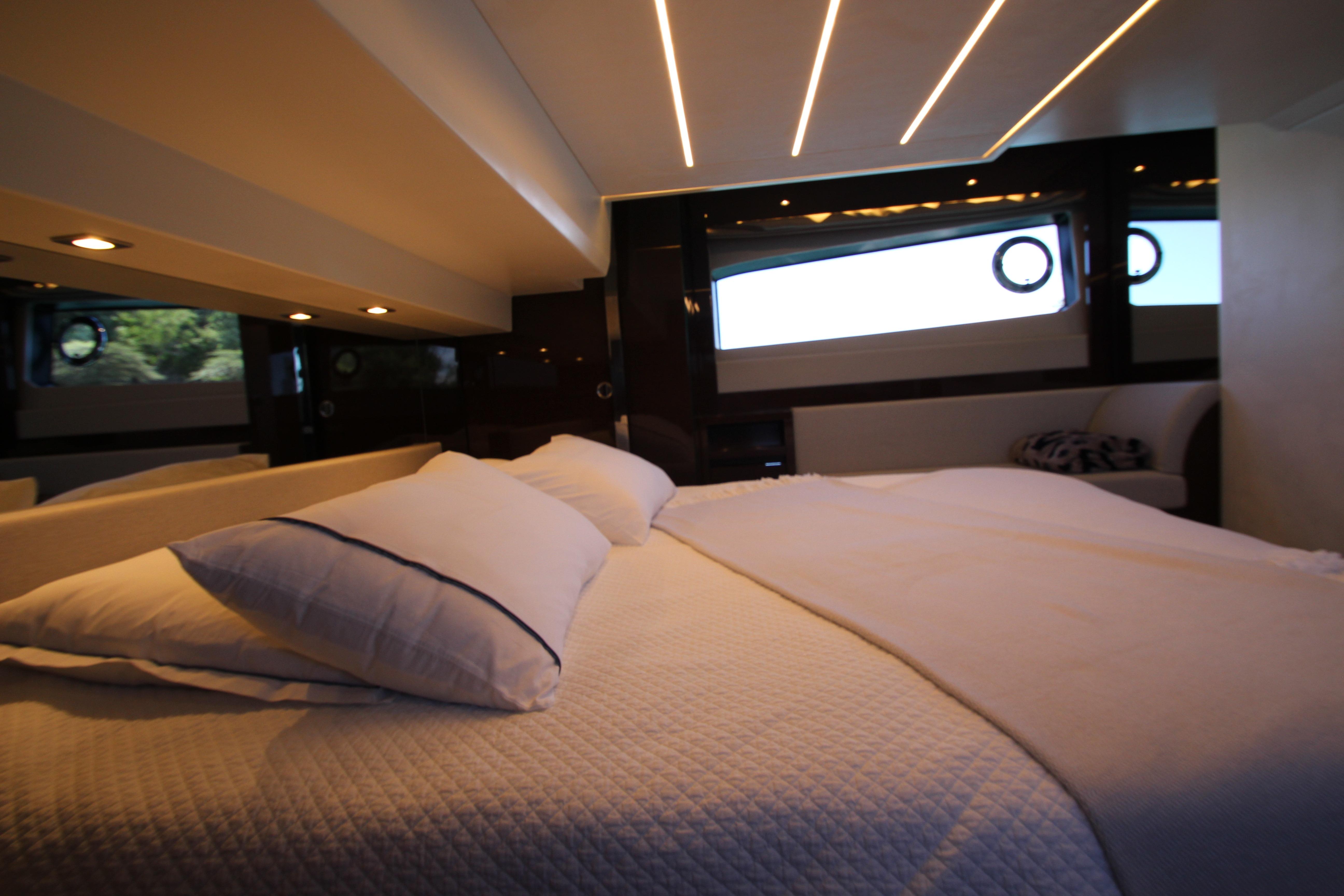 Luxurious bedroom interior of 2022 Prestige 520 yacht with modern lighting and elegant bedding.