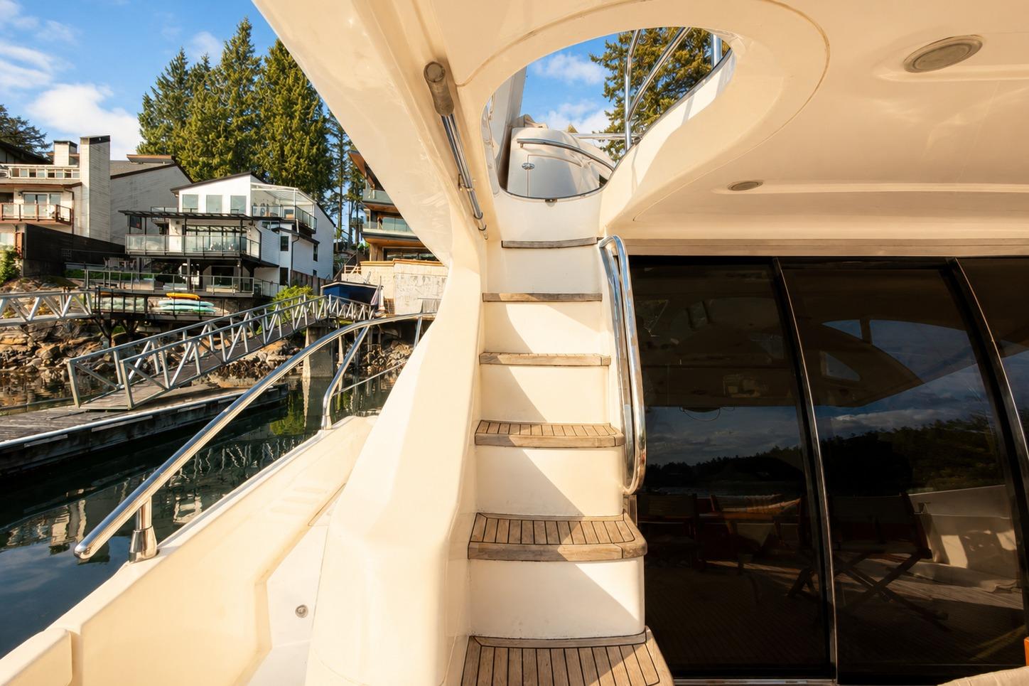 Staircase on 2005 Azimut Fly 62 yacht, docked near modern waterfront homes.