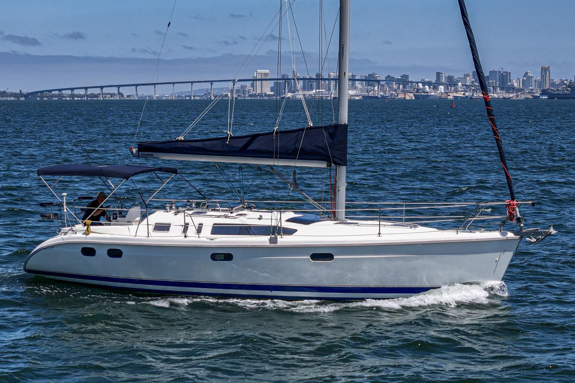 Sailing yacht Hunter 376, 1996 model, cruising on open water with city skyline backdrop.