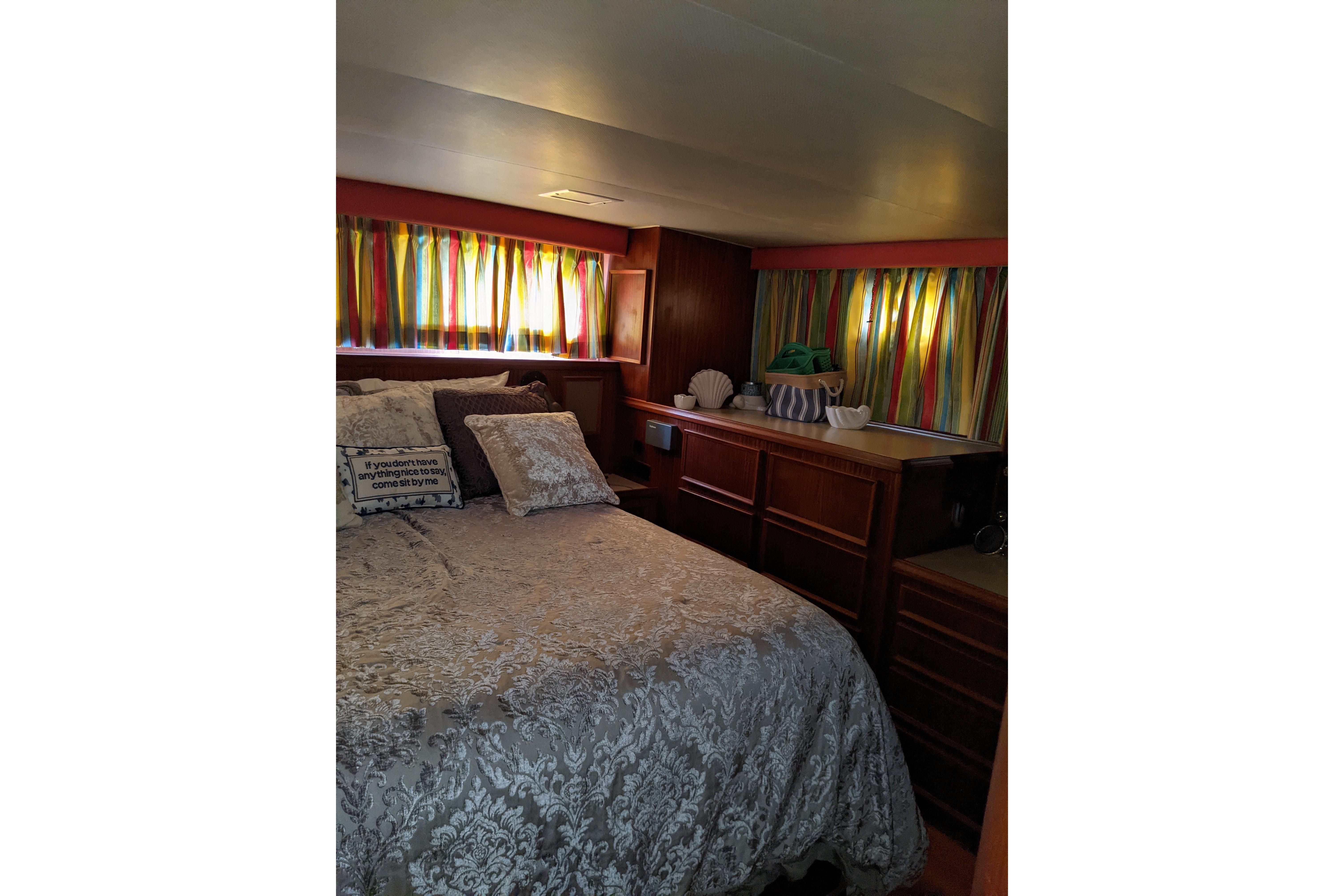 Cozy bedroom in 1984 Hatteras 53 Motor Yacht with colorful curtains and elegant bedding.