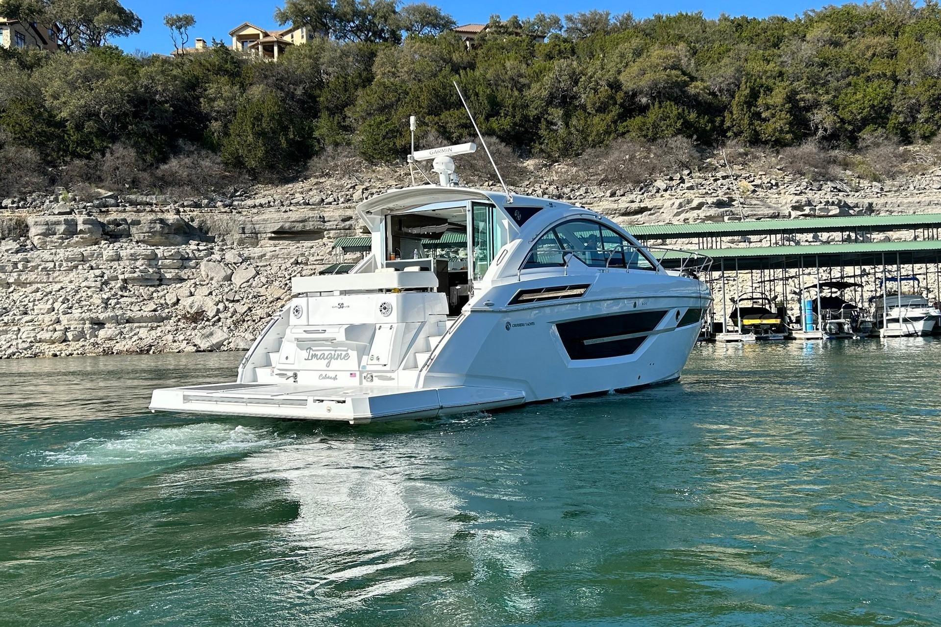 2021 Cruisers Yachts 50 Cantius on a scenic lake with rocky shoreline.