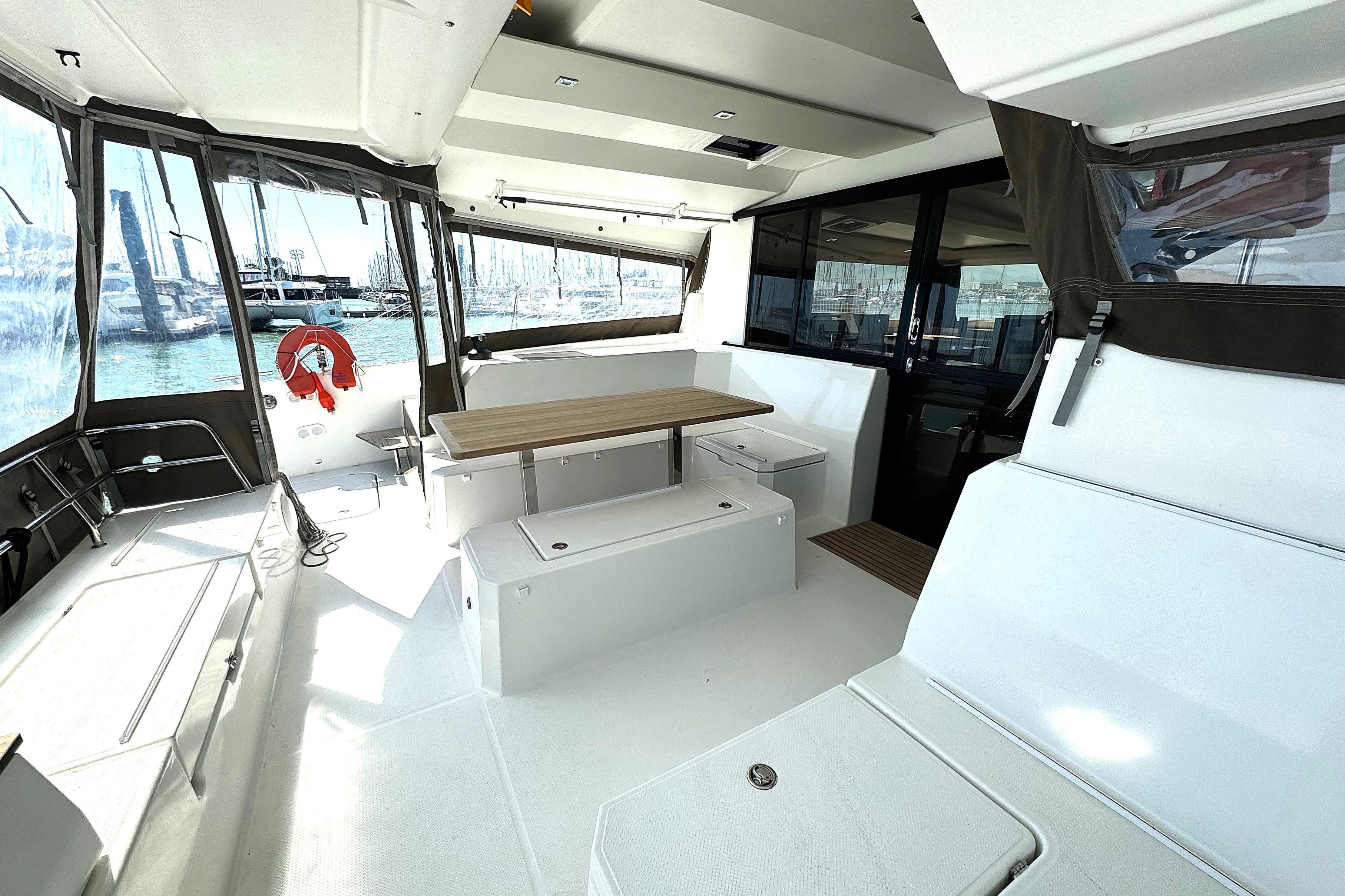 2019 Fountaine Pajot Astrea 42 Catamaran interior with seating, table, and marina view.
