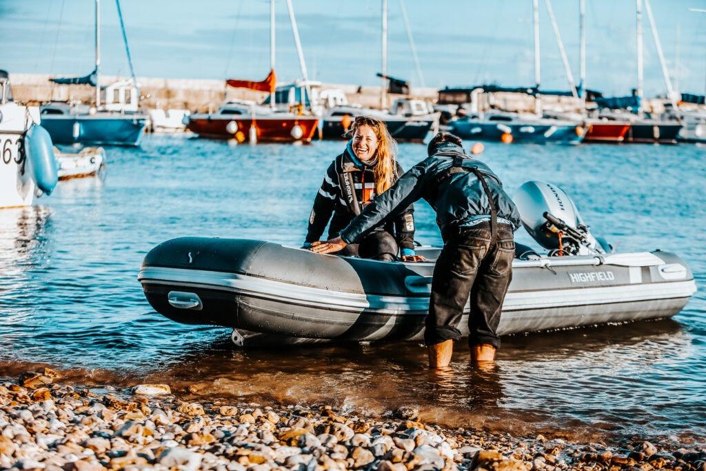 Two people on a Highfield Classic 360 boat at the beach.