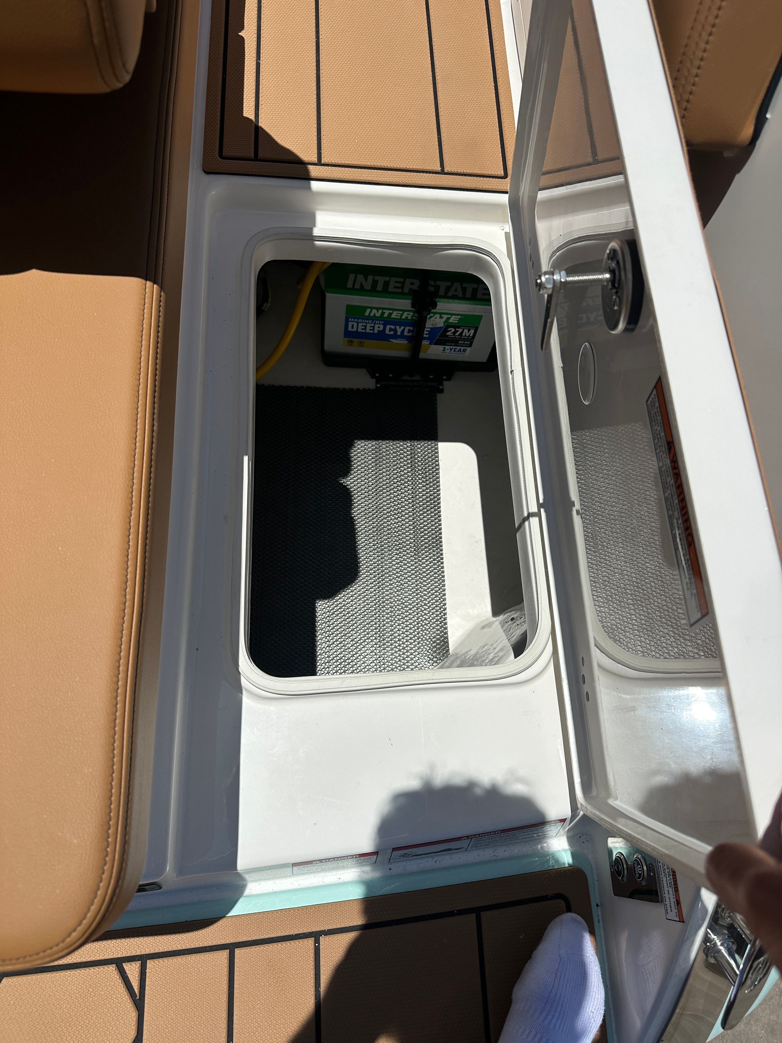 An open storage compartment on a boat with a battery inside.