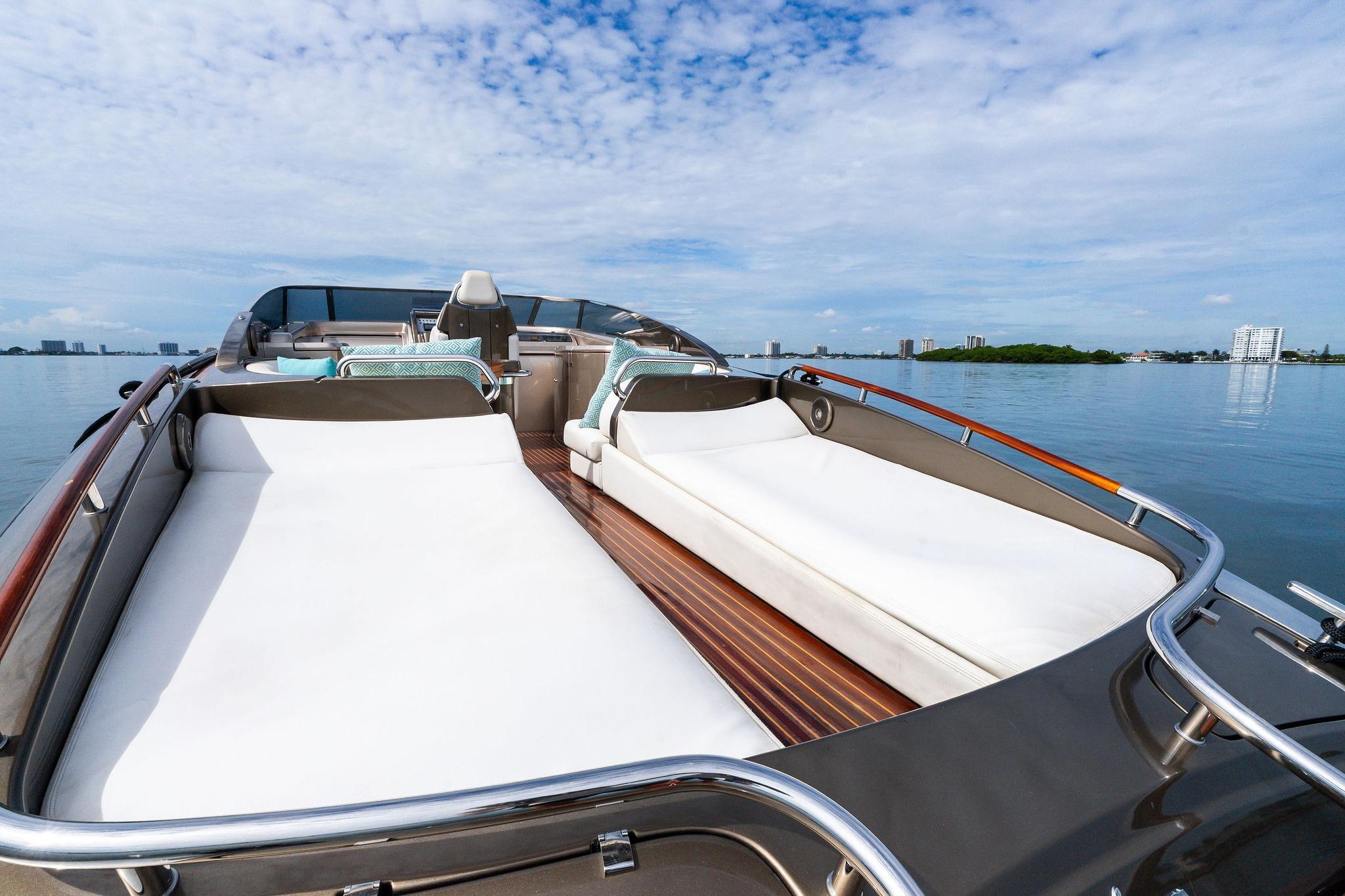 Luxurious 2014 Riva Rivarama yacht with sunbeds on calm water, under a clear blue sky.