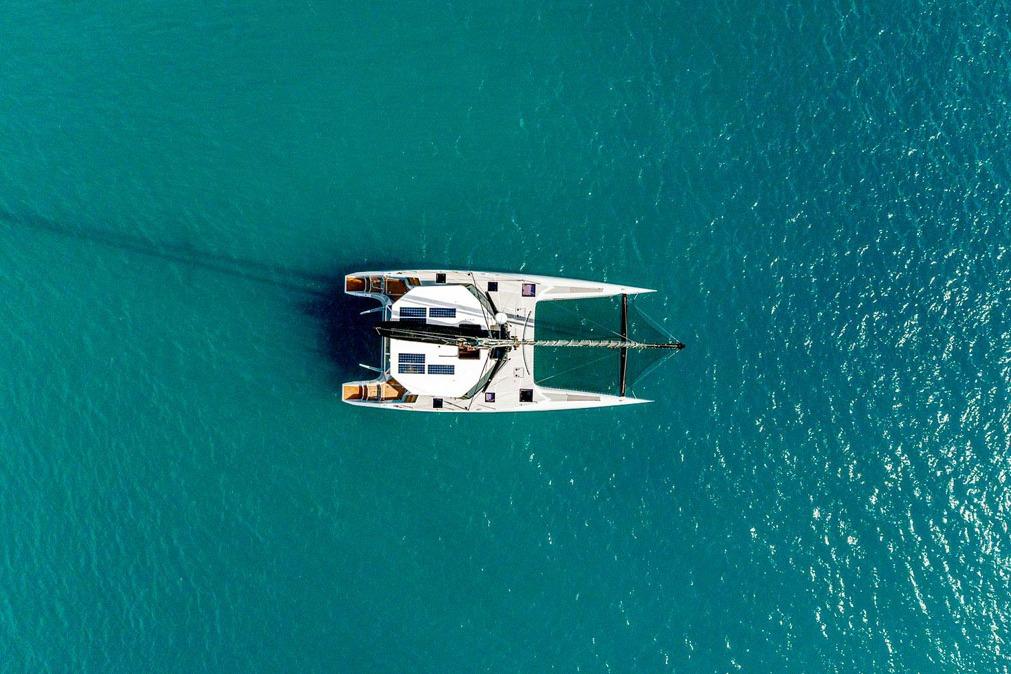 Aerial view of 2018 Gunboat 57 catamaran sailing on clear turquoise water.