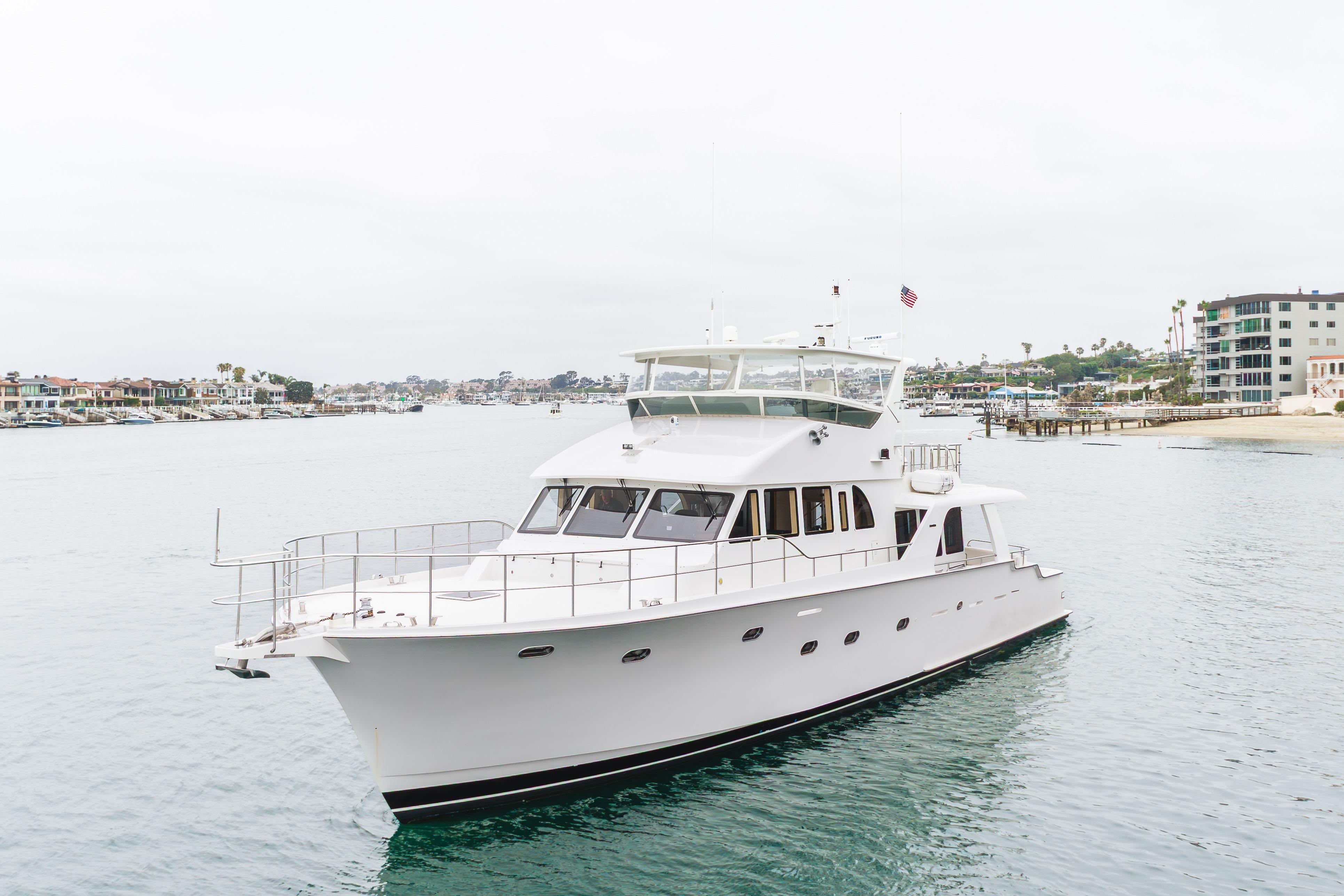 2006 Cheoy Lee 72' Raised Pilot House yacht cruising near coastal homes.