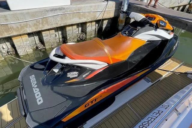 Orange and black Sea-Doo GTI jet ski docked on a wooden platform.